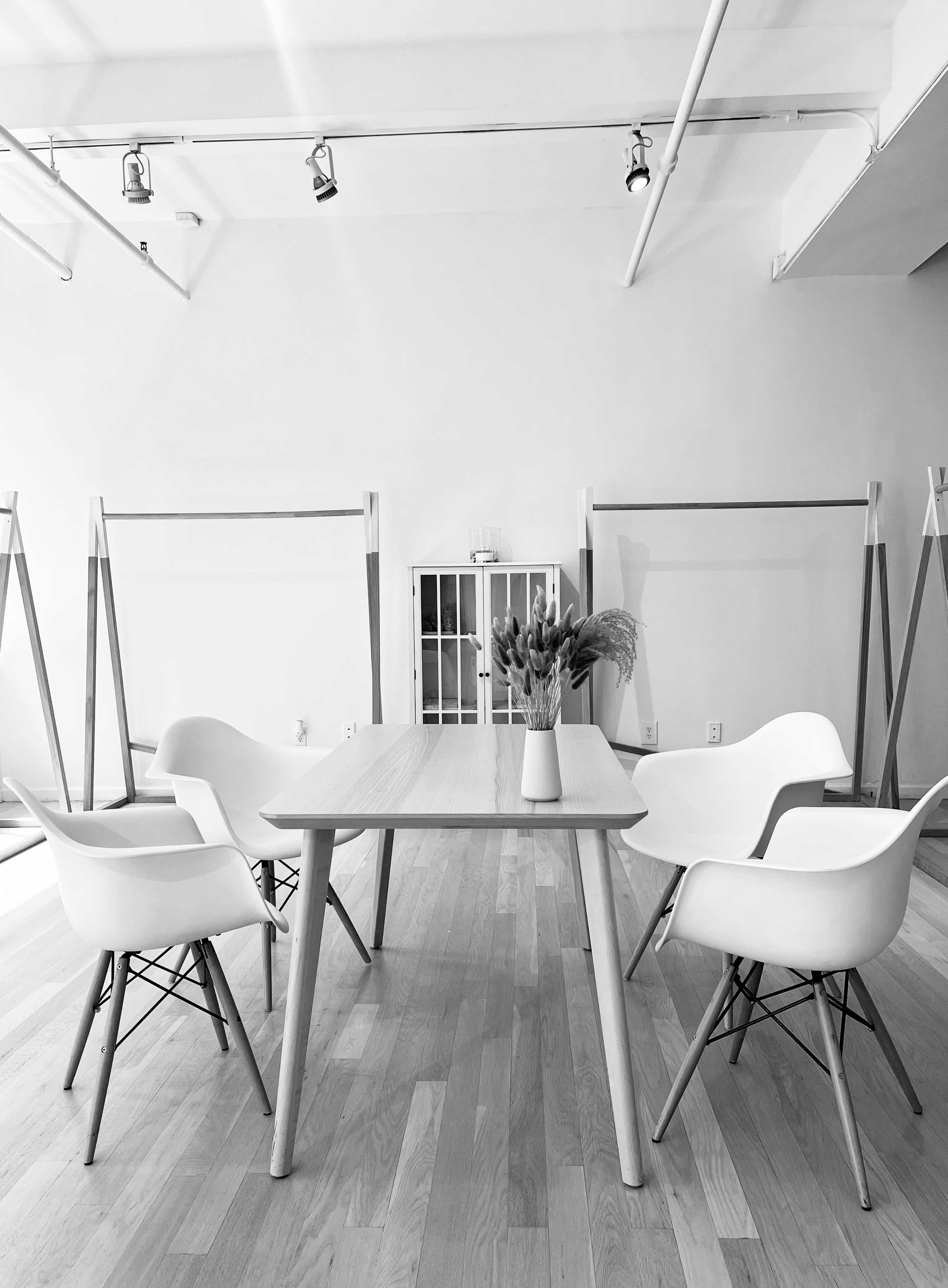 A light-filled room features a wooden table surrounded by four white chairs.