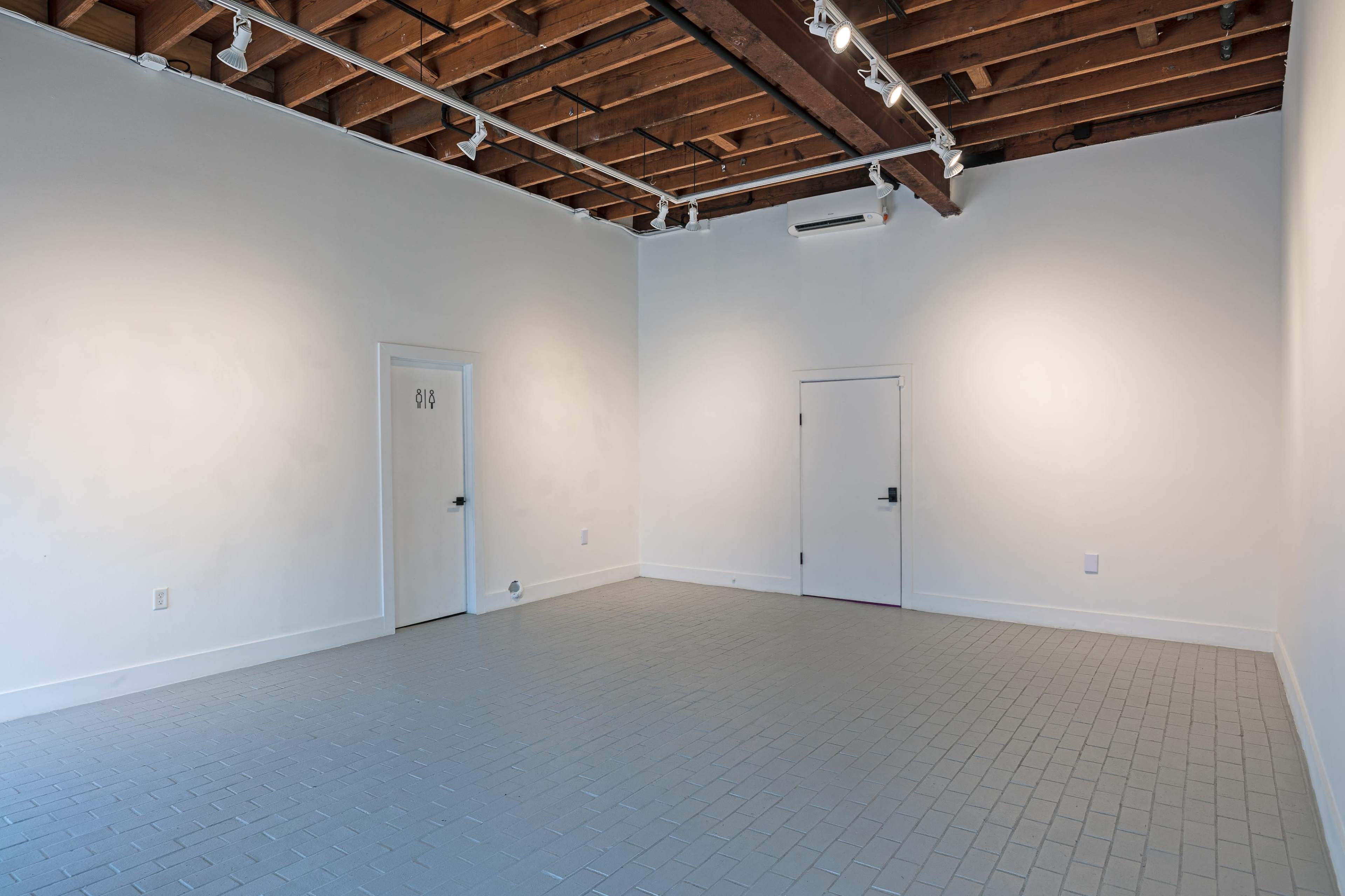 An empty room with gray tiled flooring, white walls, and two doors against one wall.