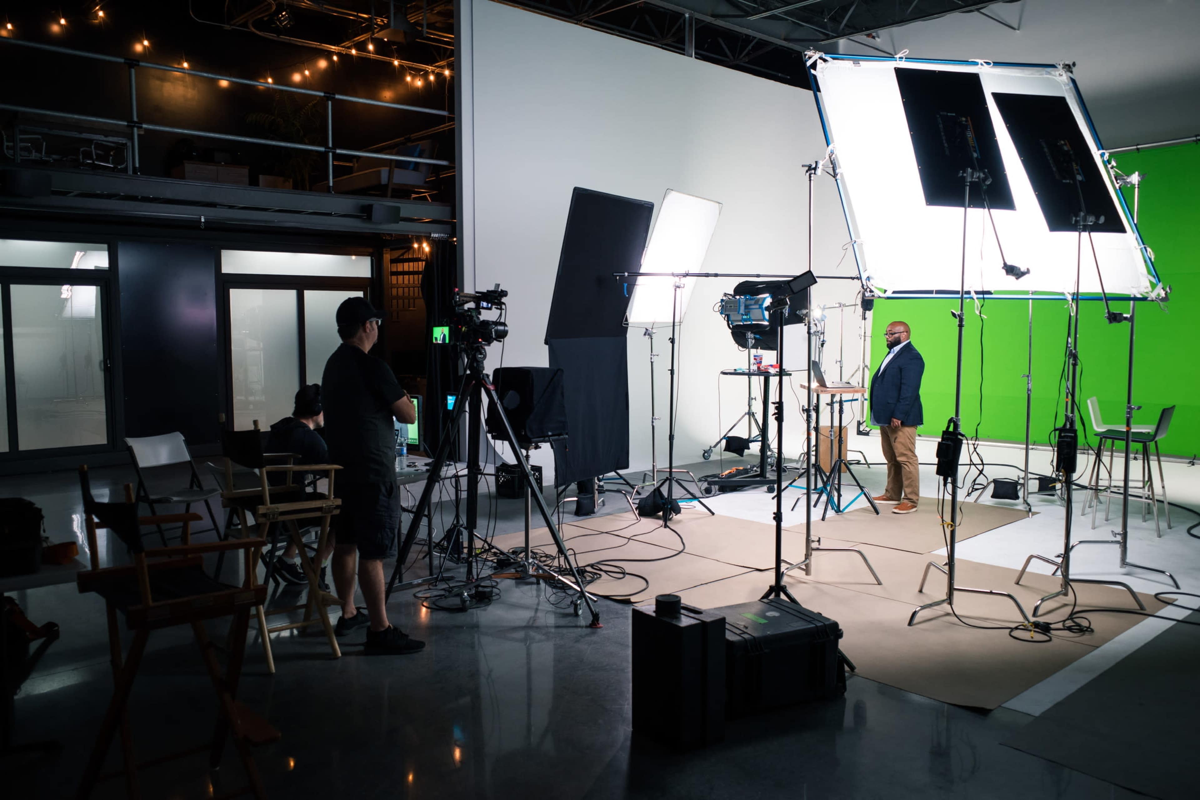 A film set is prepared with cameras, lights, and a green screen for a video shoot.