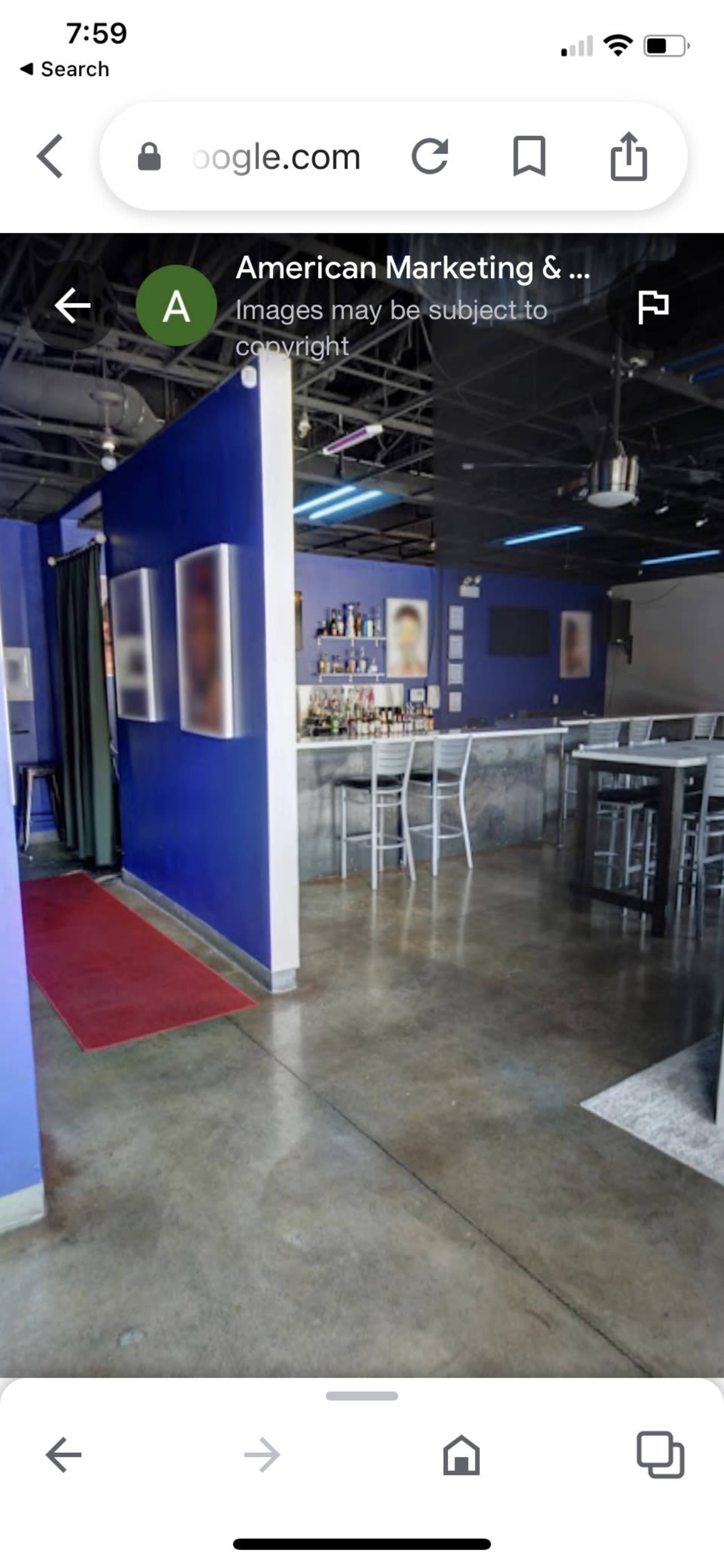 A bar area with a polished concrete floor, blue walls, and a long counter with bar stools.
