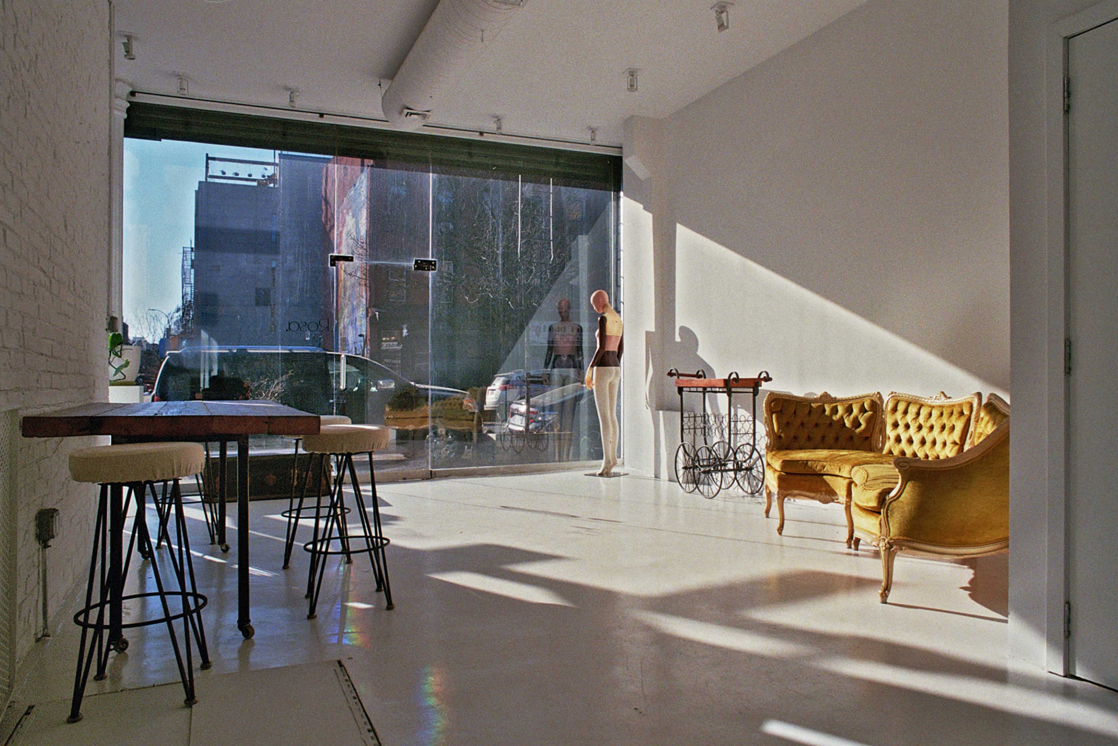 The image shows a modern interior space with a yellow couch and a wooden table, featuring a large window that lets in natural light.