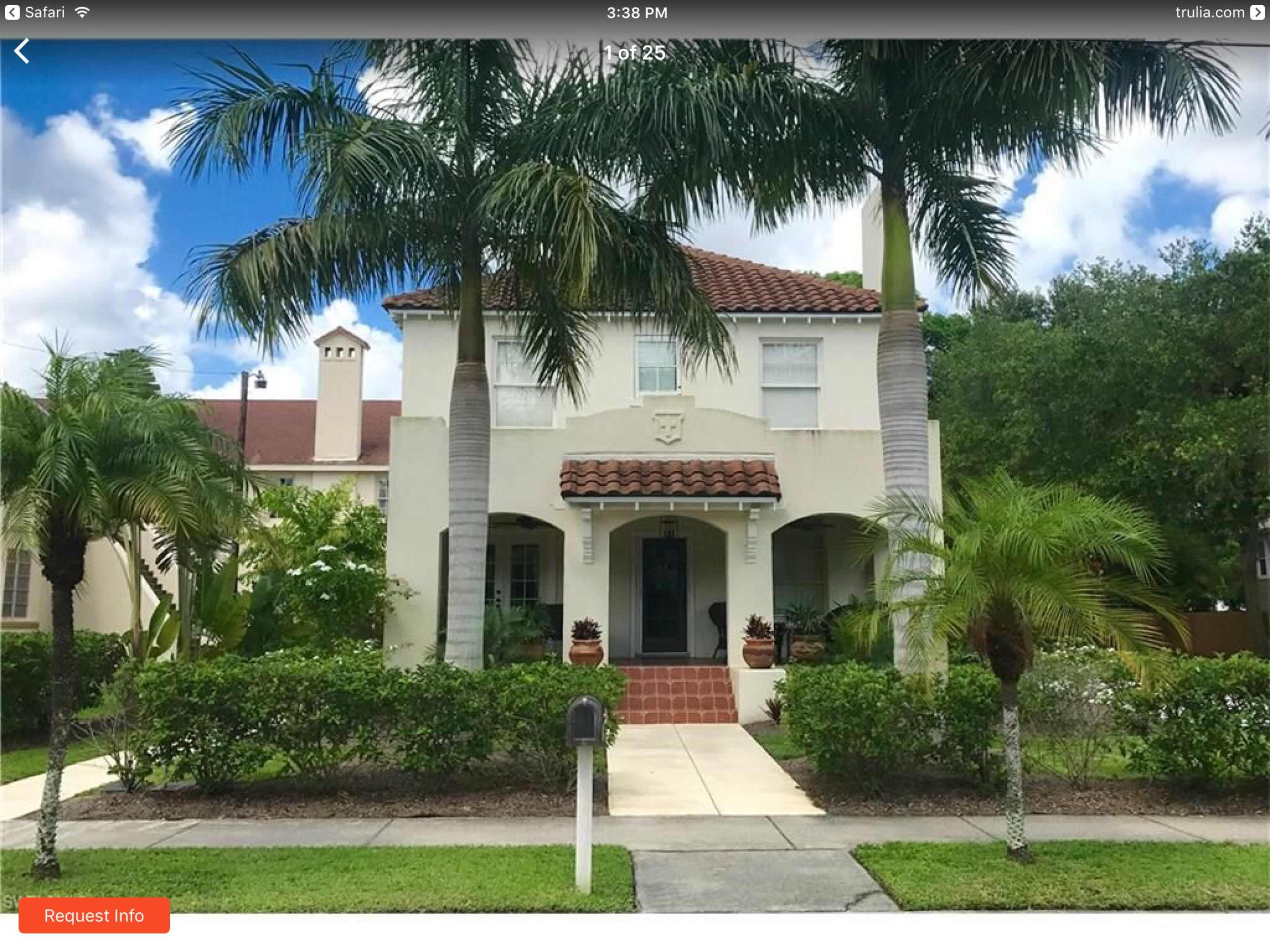 A two-story house with a tile roof and palm trees in the front yard is surrounded by well-maintained landscaping.