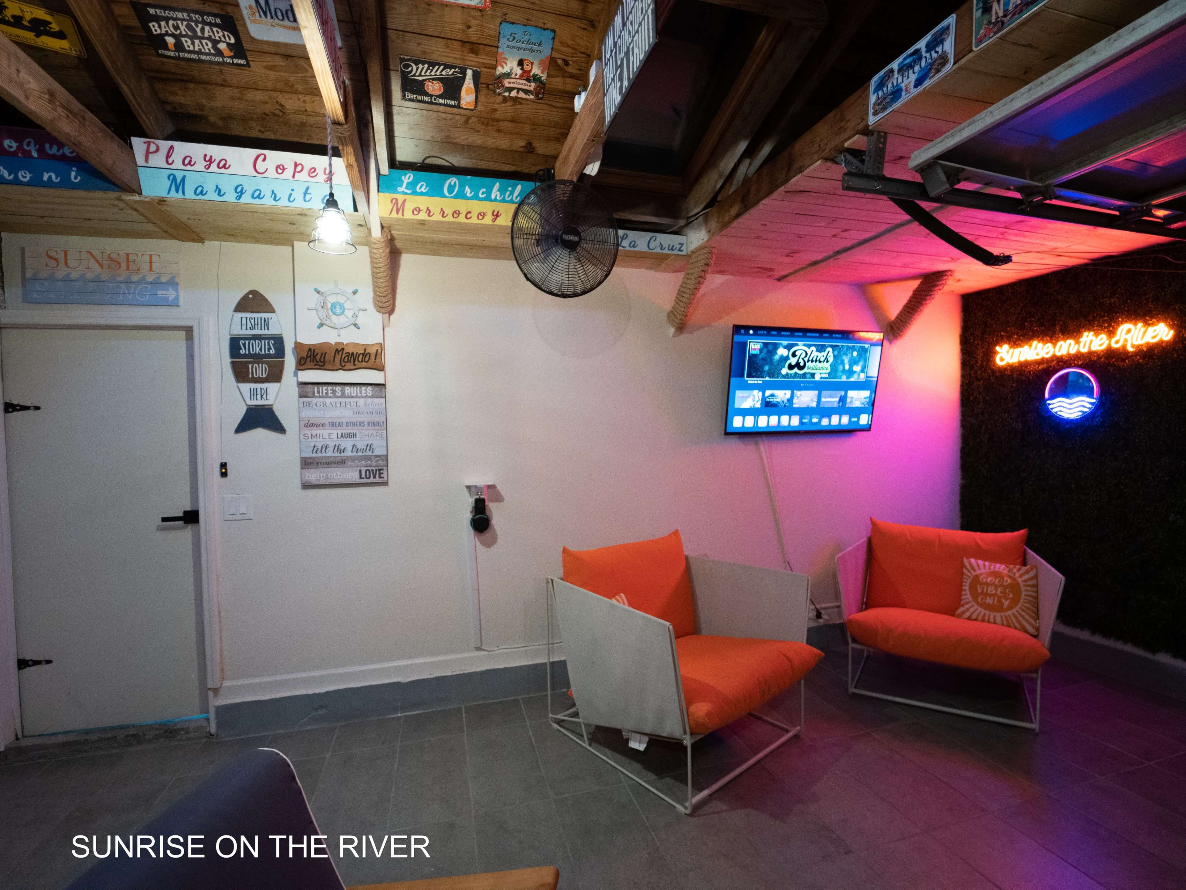 A cozy indoor space with a television, orange seating, and decorative signs on the walls.