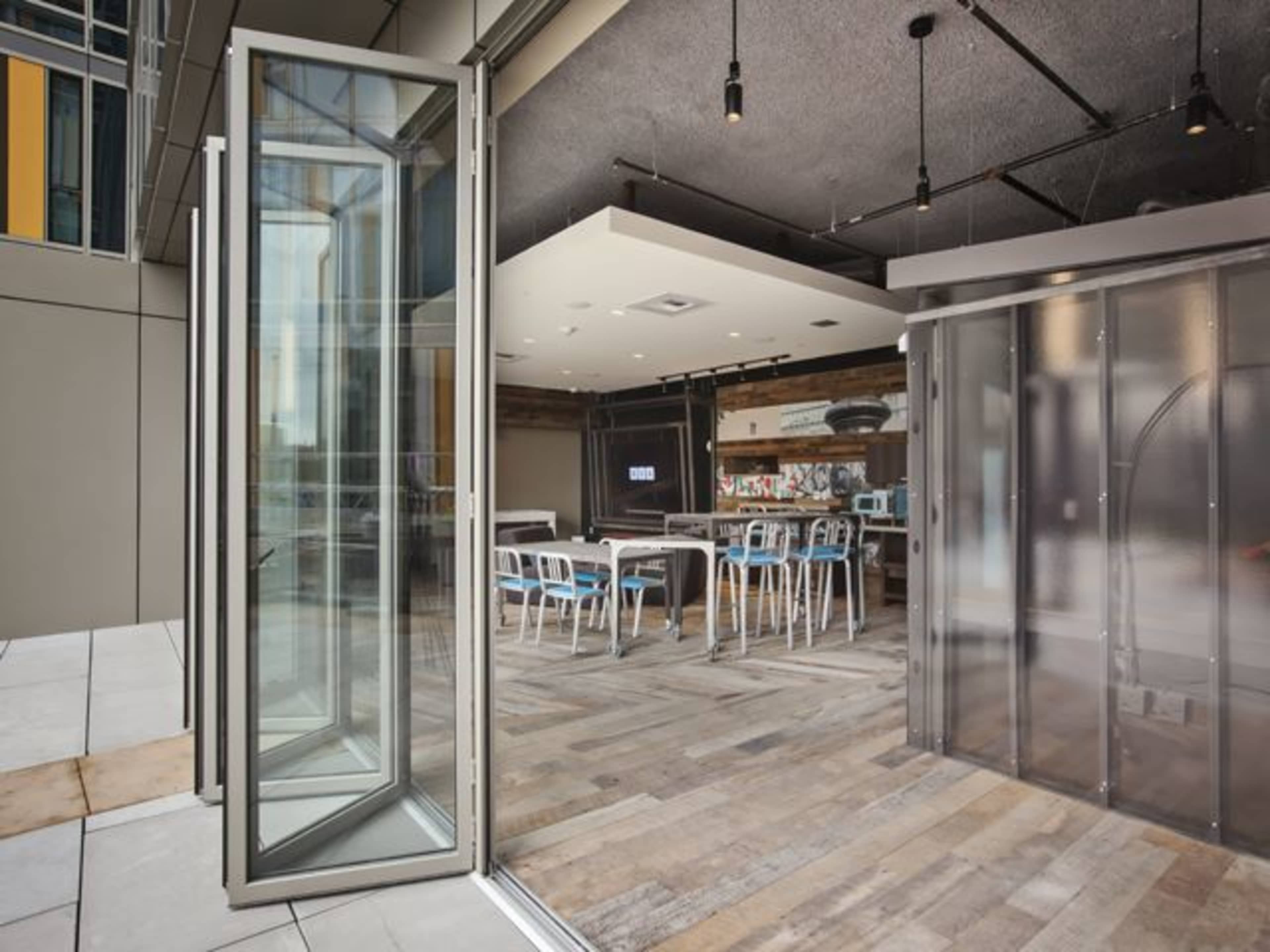 A modern workspace featuring glass doors, a large table with chairs, and a sleek interior design.
