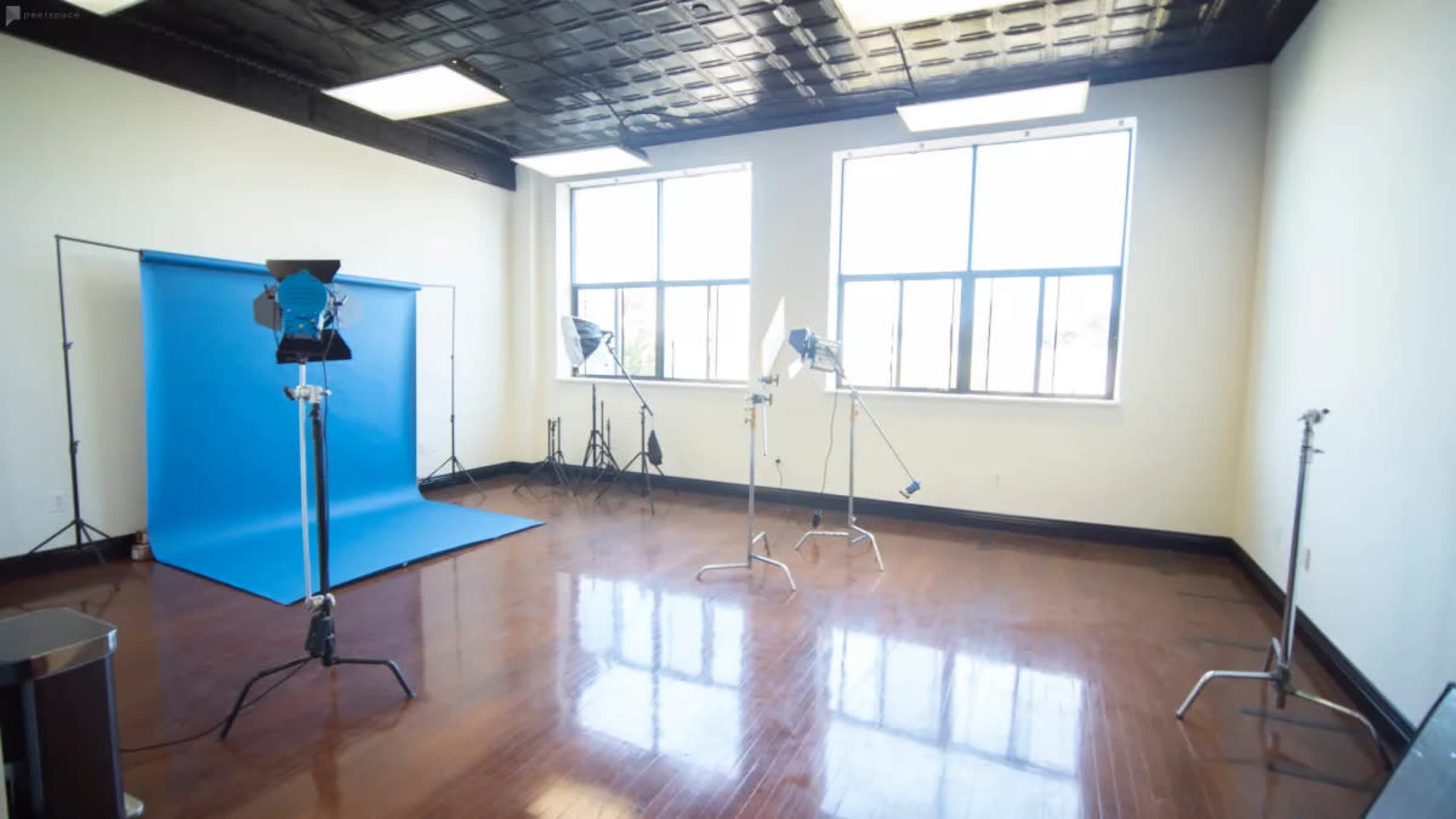 A well-lit photography studio with a blue backdrop and several lighting equipment setups.