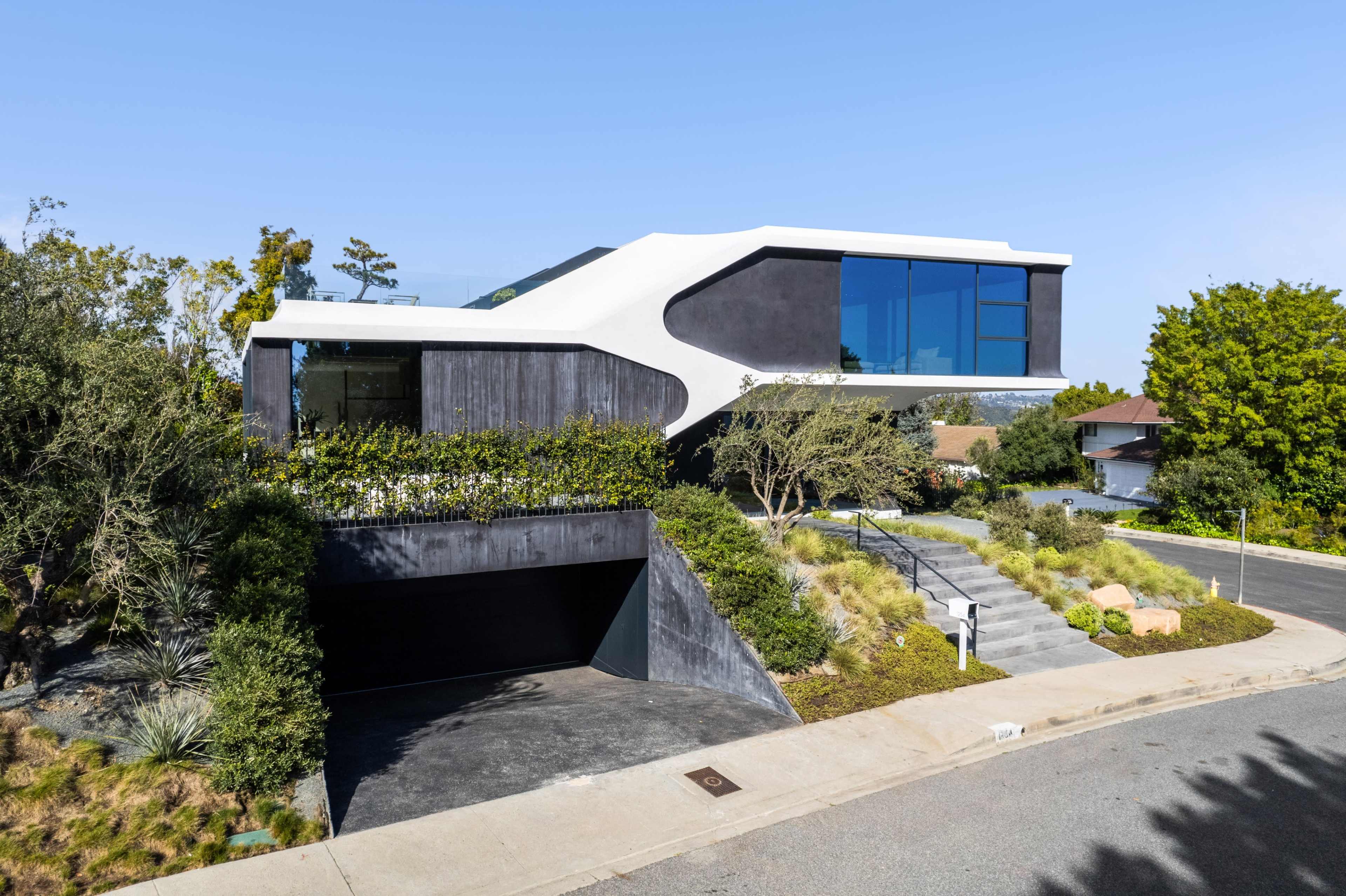 A modern two-story house features a unique architectural design with a white and black exterior, expansive windows, and a landscaped front yard.