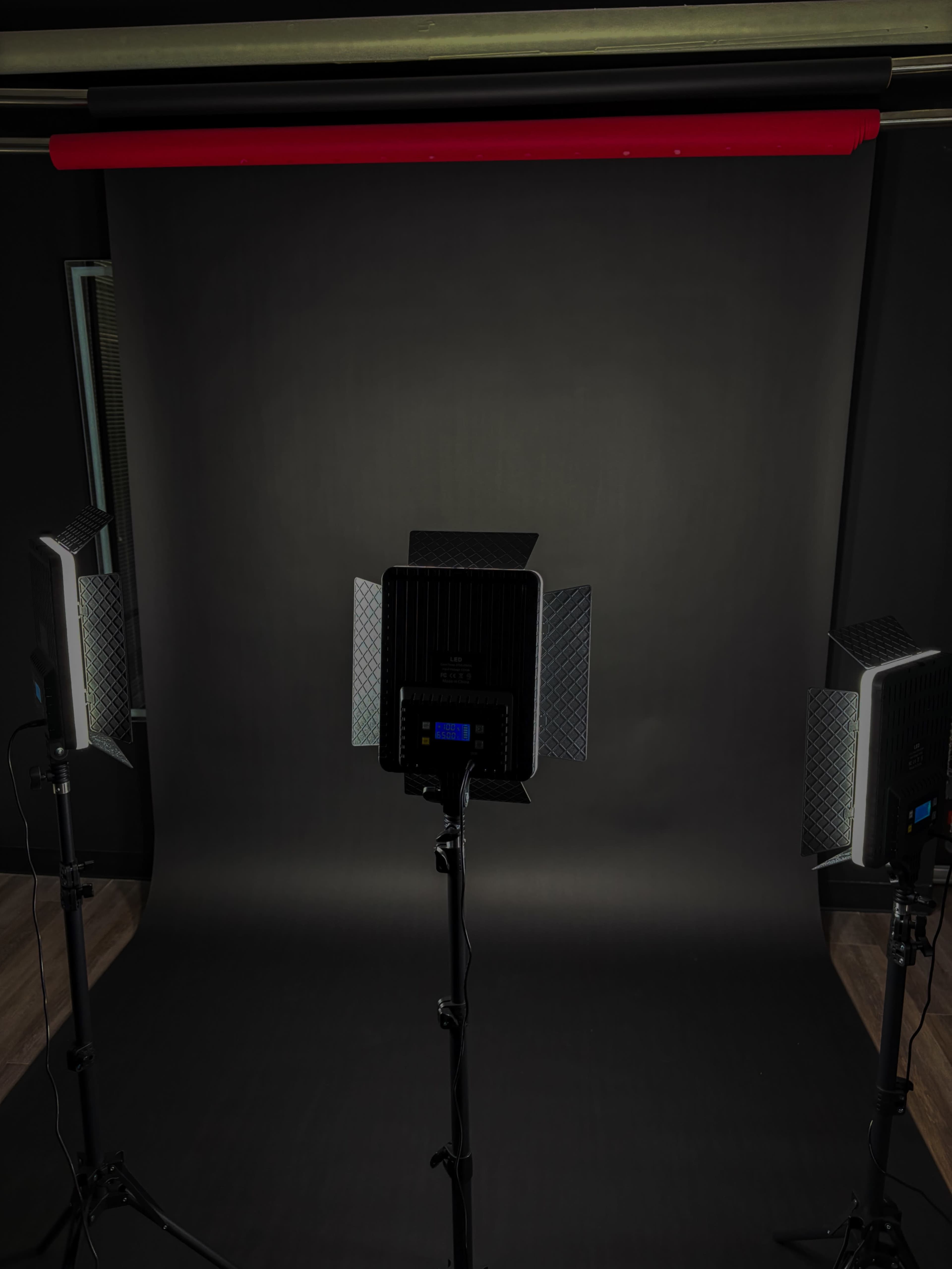 The scene shows a photography studio setup with three lighting fixtures positioned in front of a dark backdrop.