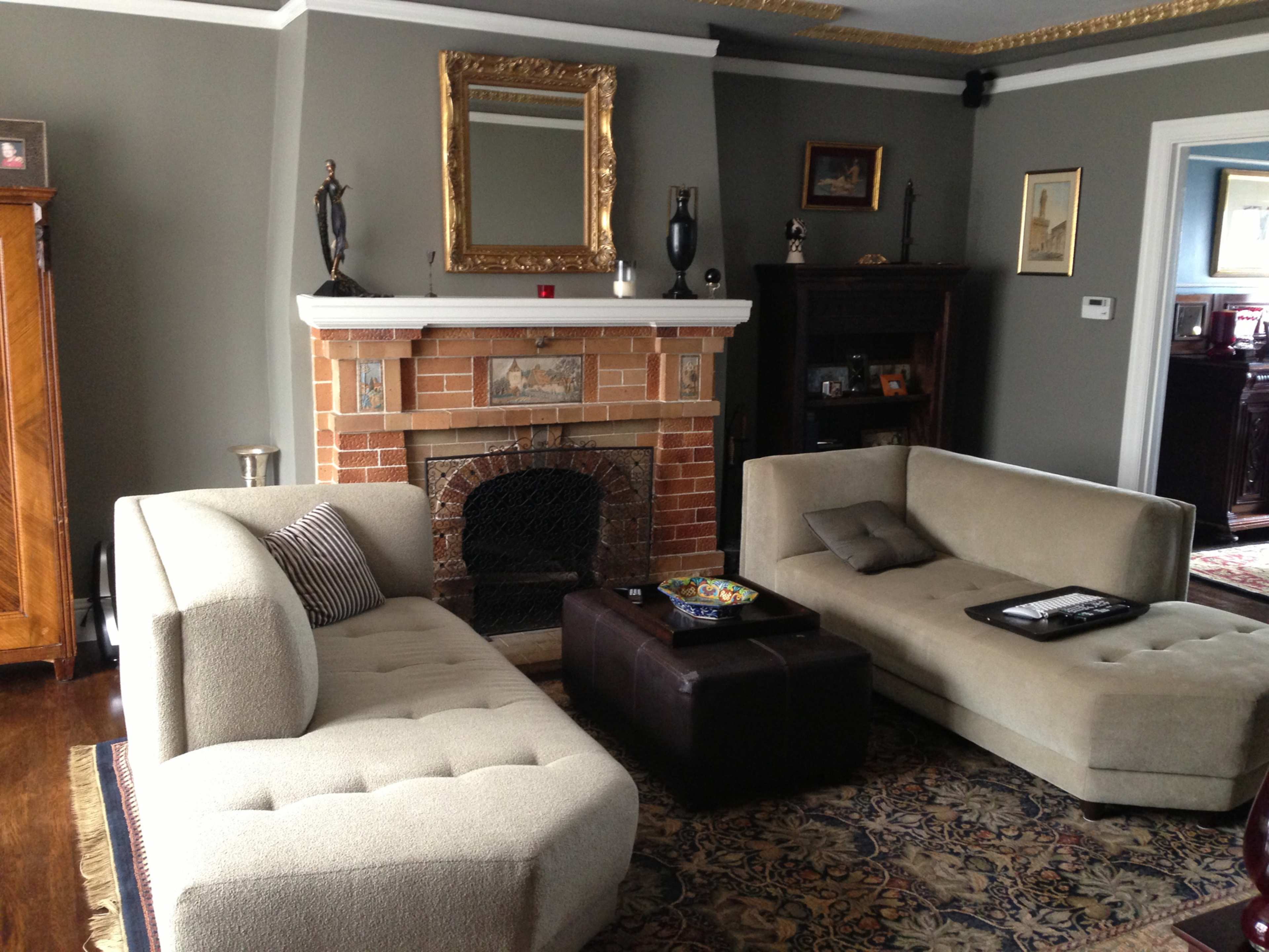 A living room with two beige sofas, a dark coffee table, and a fireplace surrounded by a gray wall and decorative elements.