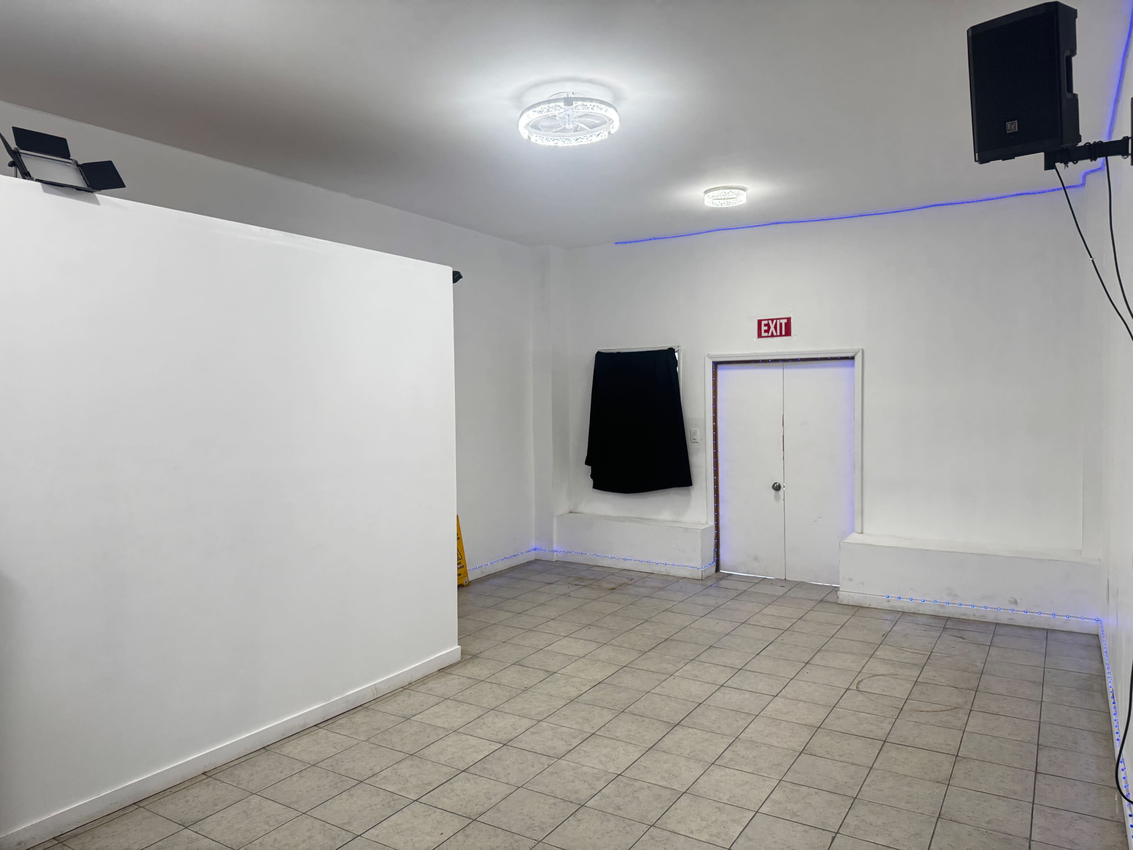 The image shows an empty room with white walls, a tiled floor, a closed door, and a black curtain covering a window.