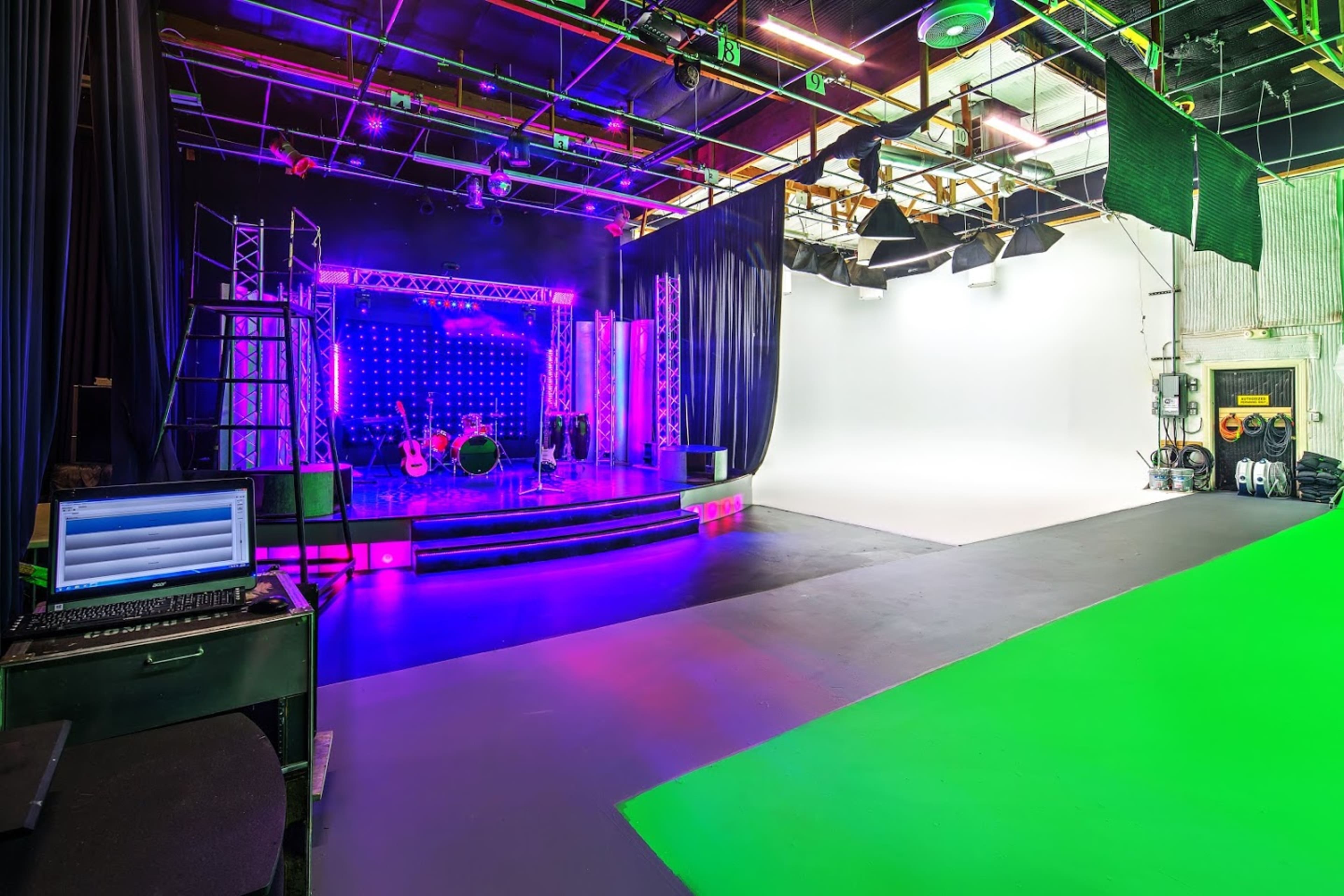 A production studio with a colorful stage setup on one side and a green screen area on the other.