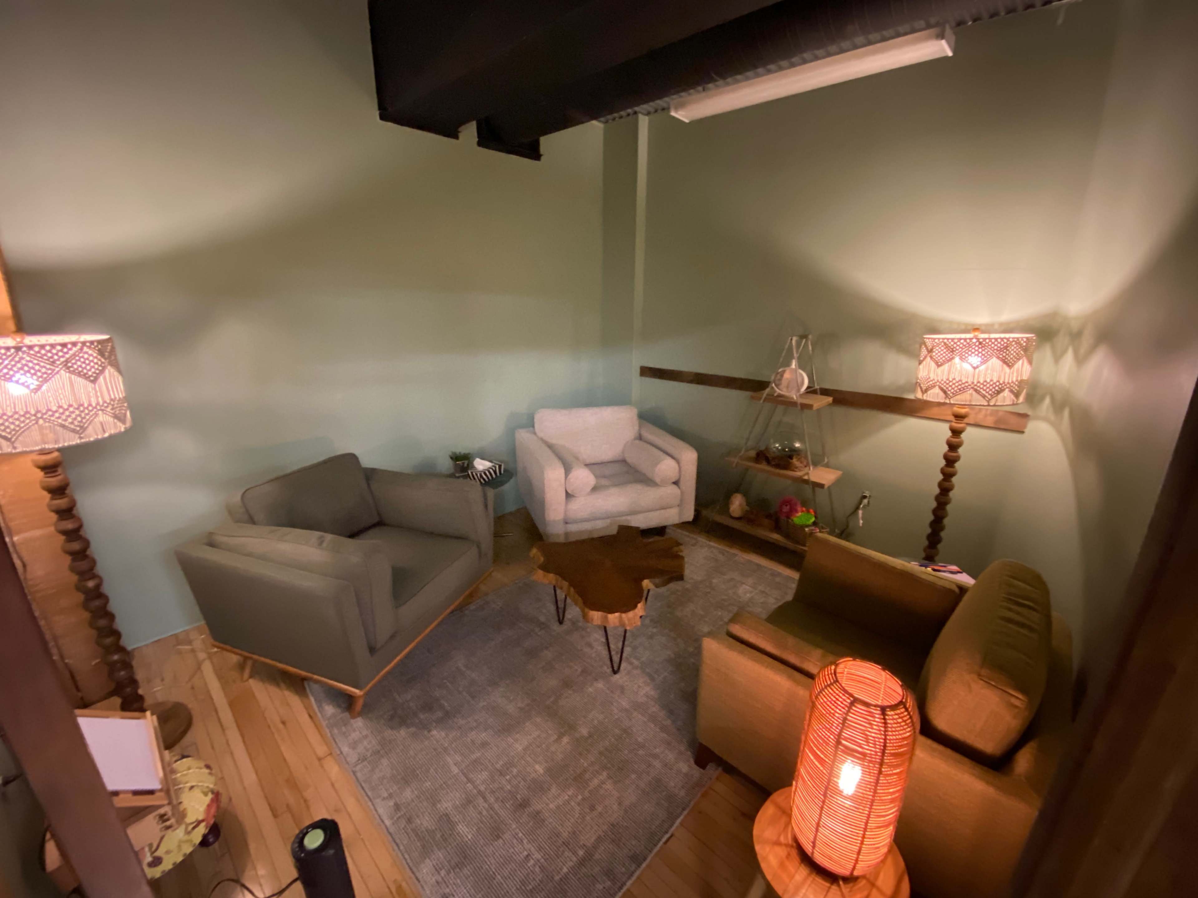 A cozy interior living space featuring three upholstered chairs, a wooden coffee table, and two decorative lamps.