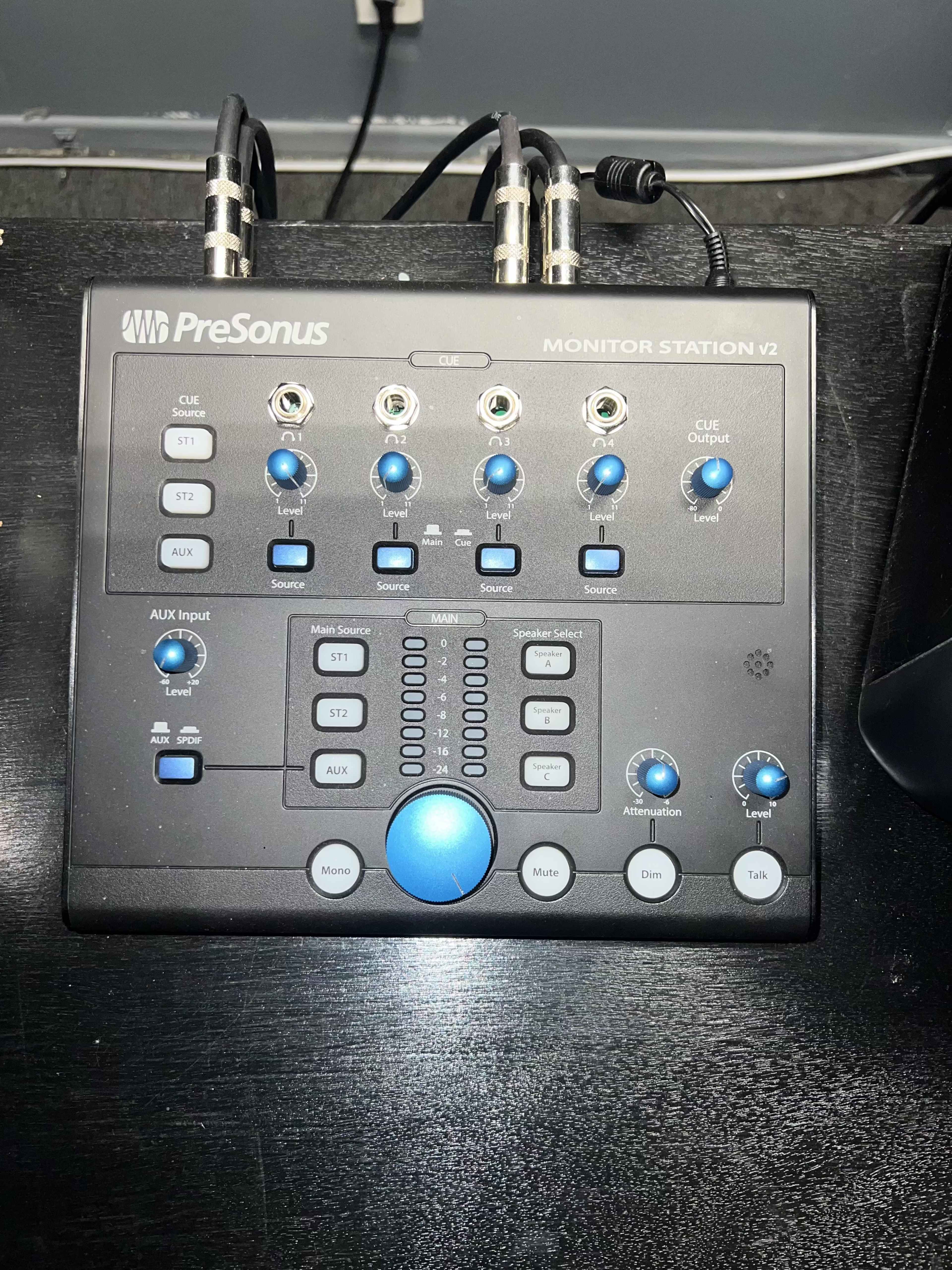 A PreSonus Monitor Station V2 audio interface with various knobs and buttons for audio control.