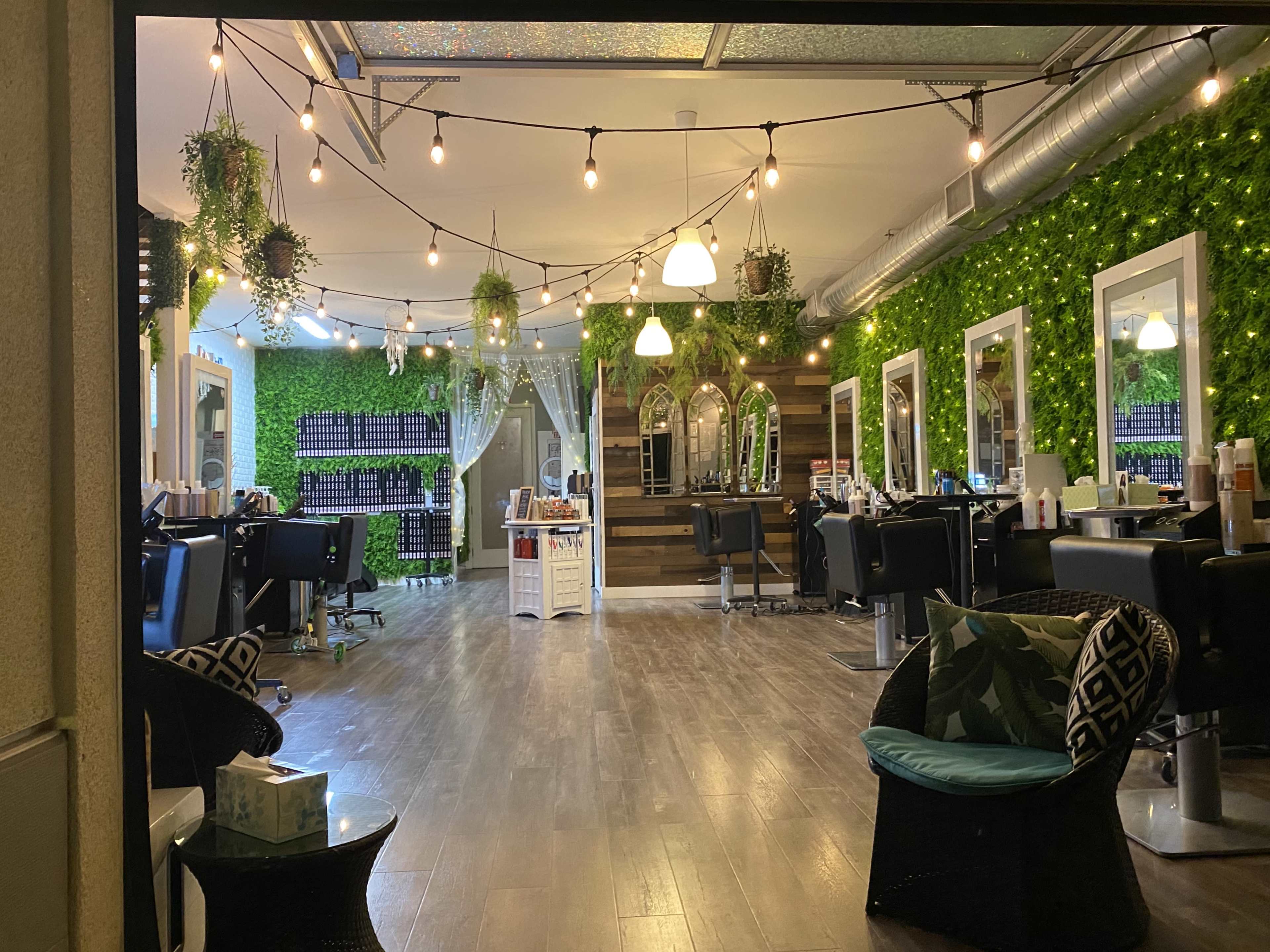 The image shows a hair salon interior featuring green wall accents, styling stations with chairs, and decorative string lights.
