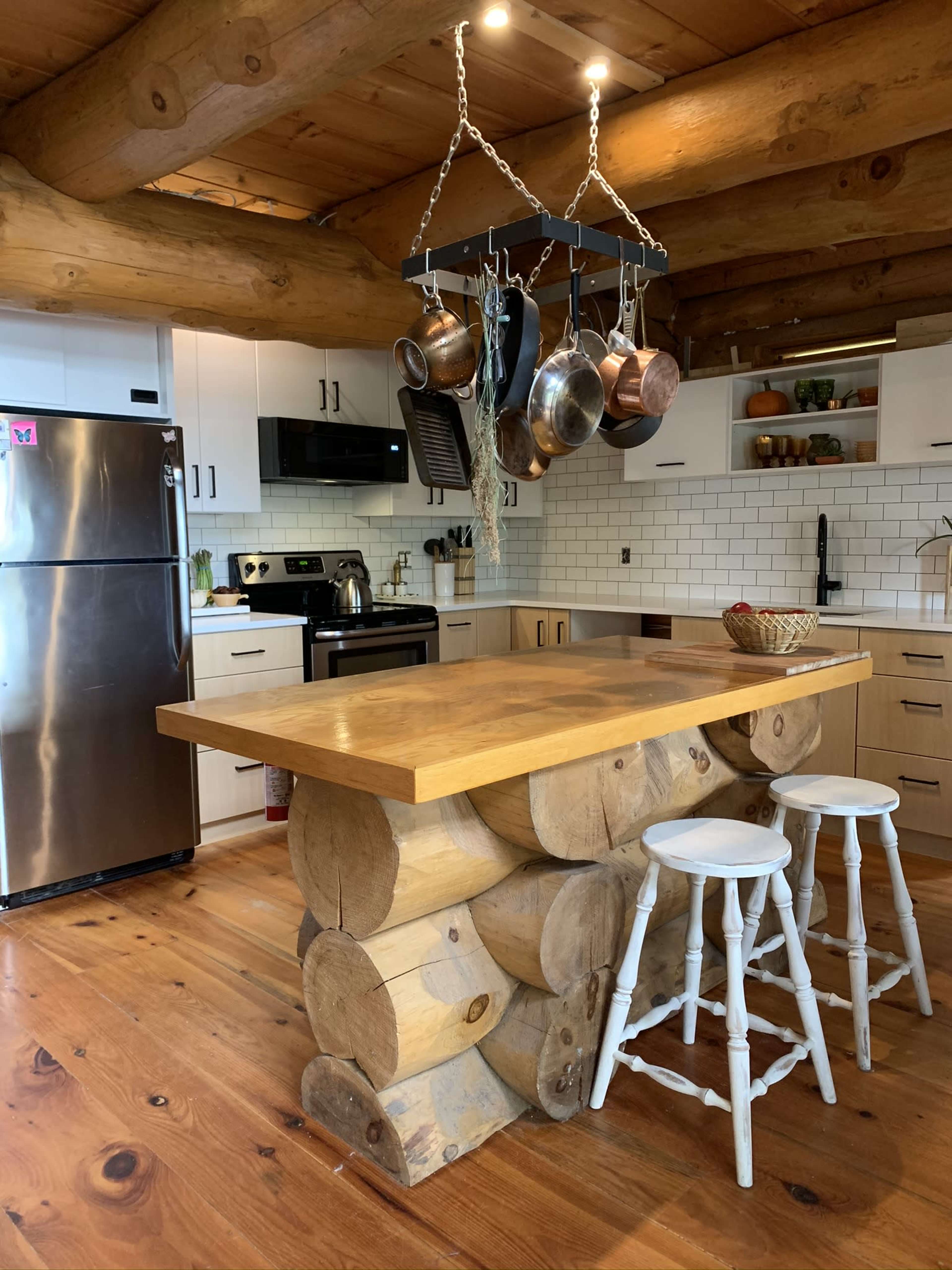 The kitchen features a log-style island with a wooden countertop, surrounded by white cabinetry and stainless steel appliances.