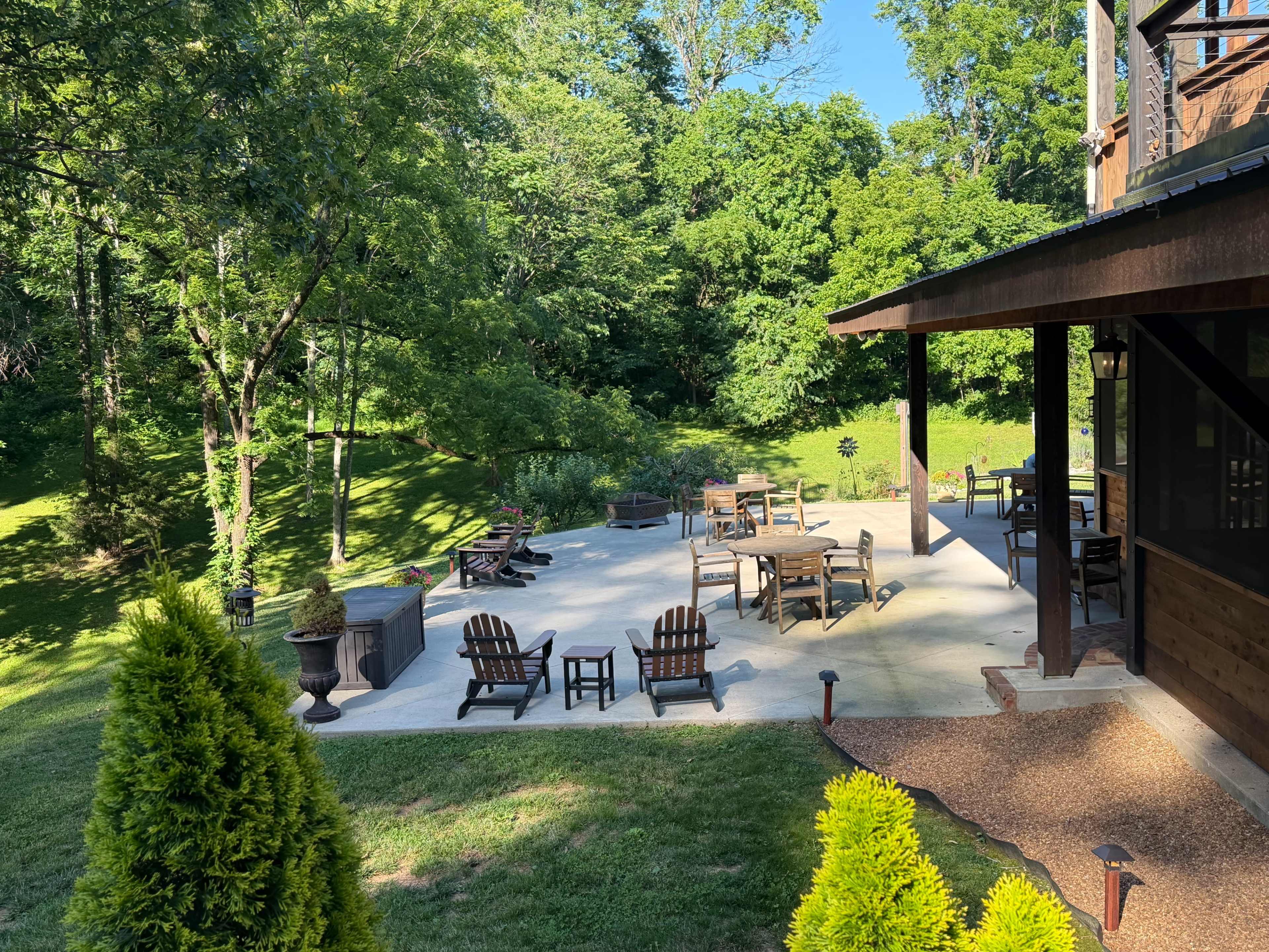 The image shows a spacious outdoor patio area with several seating arrangements and a landscaped green background.