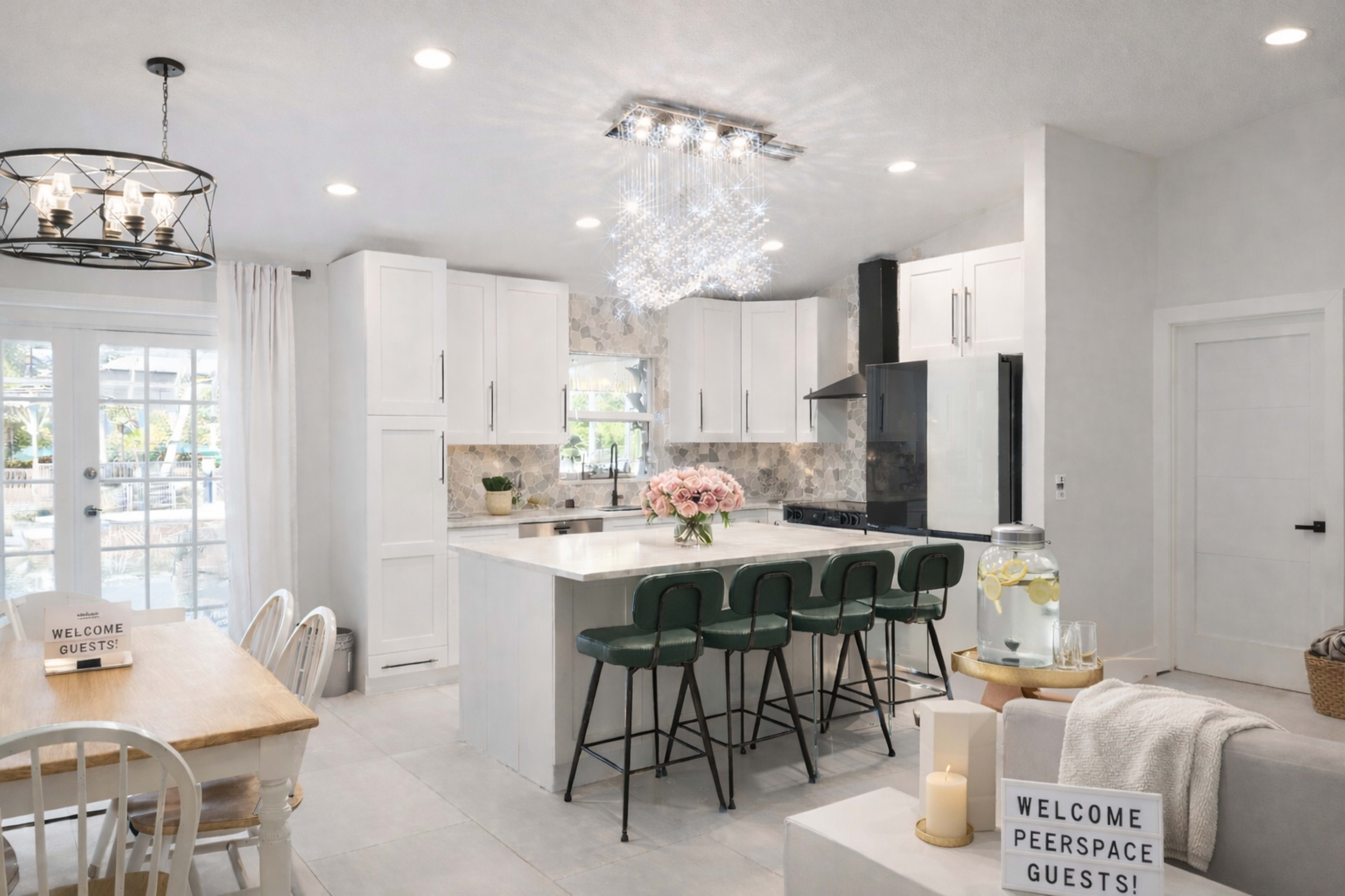 The kitchen features modern white cabinetry, a large island with green stools, and a dining area with a wooden table.