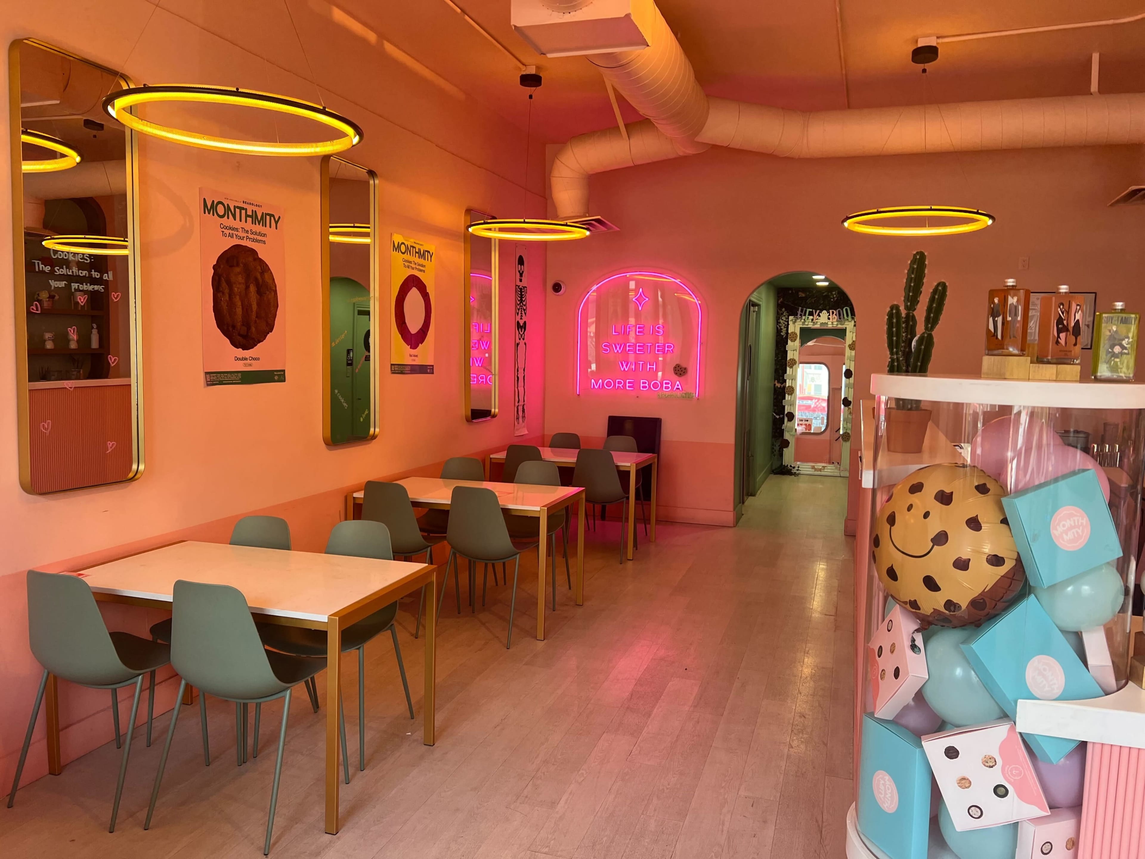 A colorful café interior featuring several tables, neon signs, and wall decorations.
