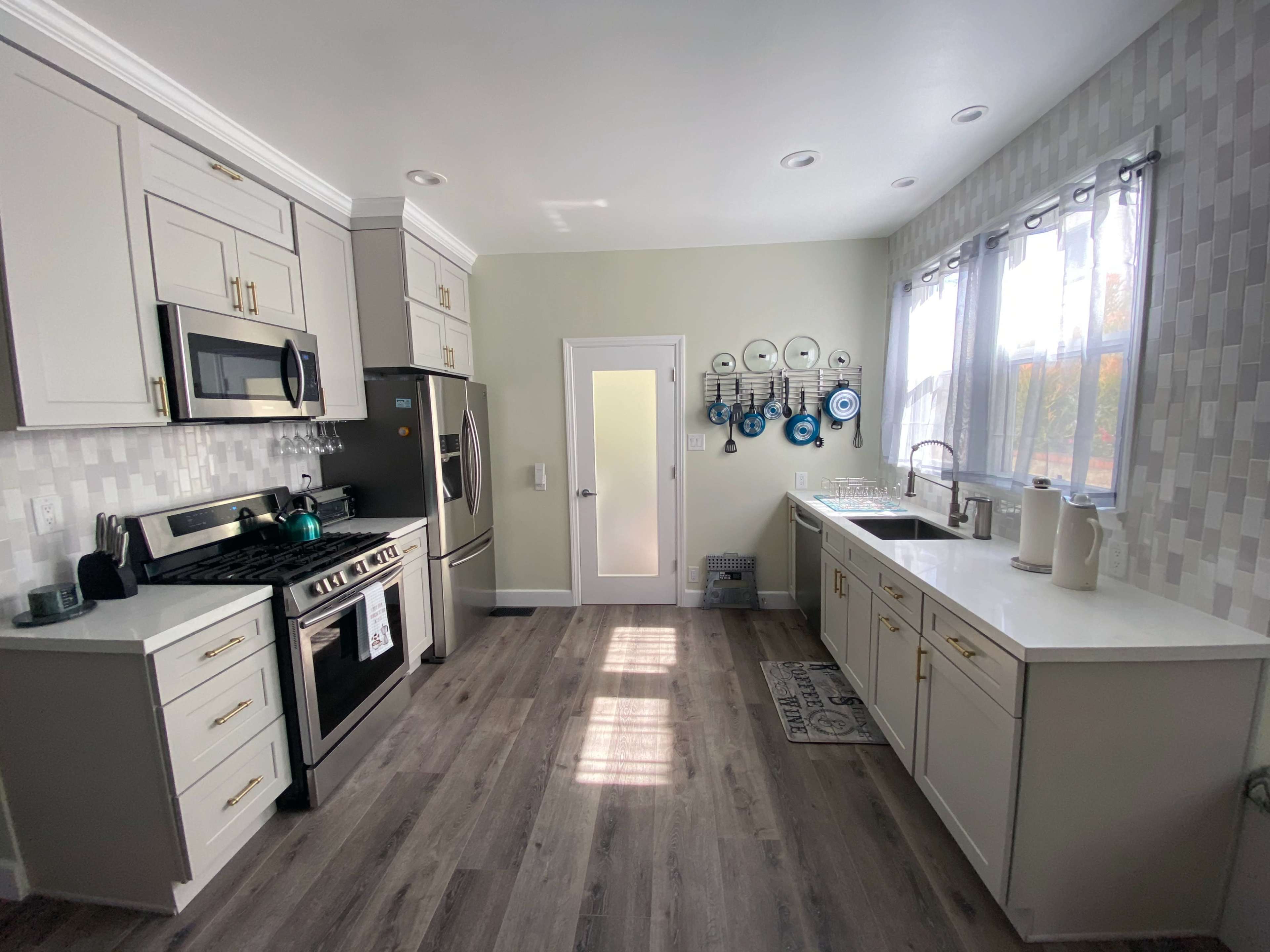 A modern kitchen features light-colored cabinetry, stainless steel appliances, and a door leading to another room.