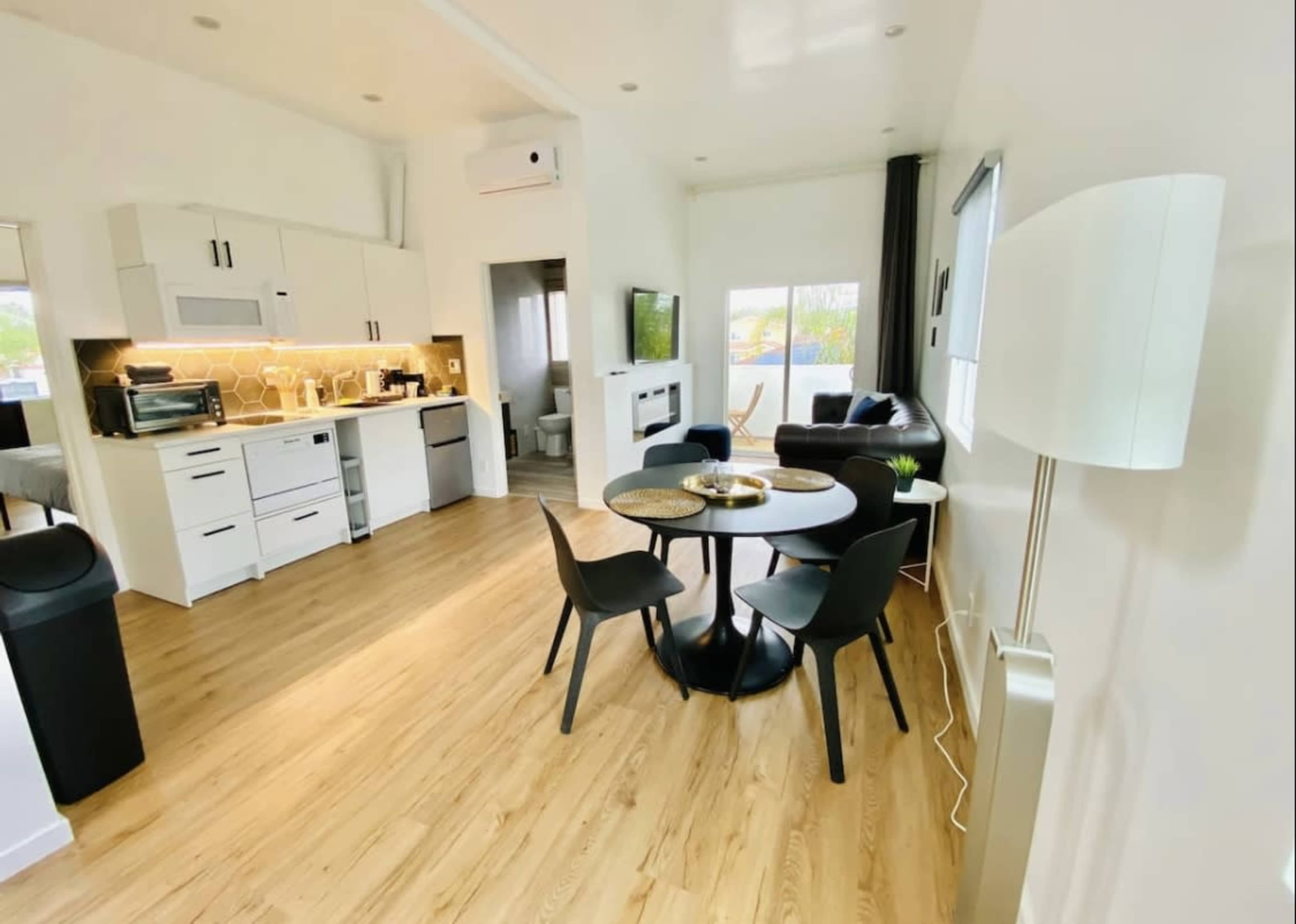 A modern, open-concept living space featuring a kitchen, dining area with a round table, and a sitting area with a sofa.