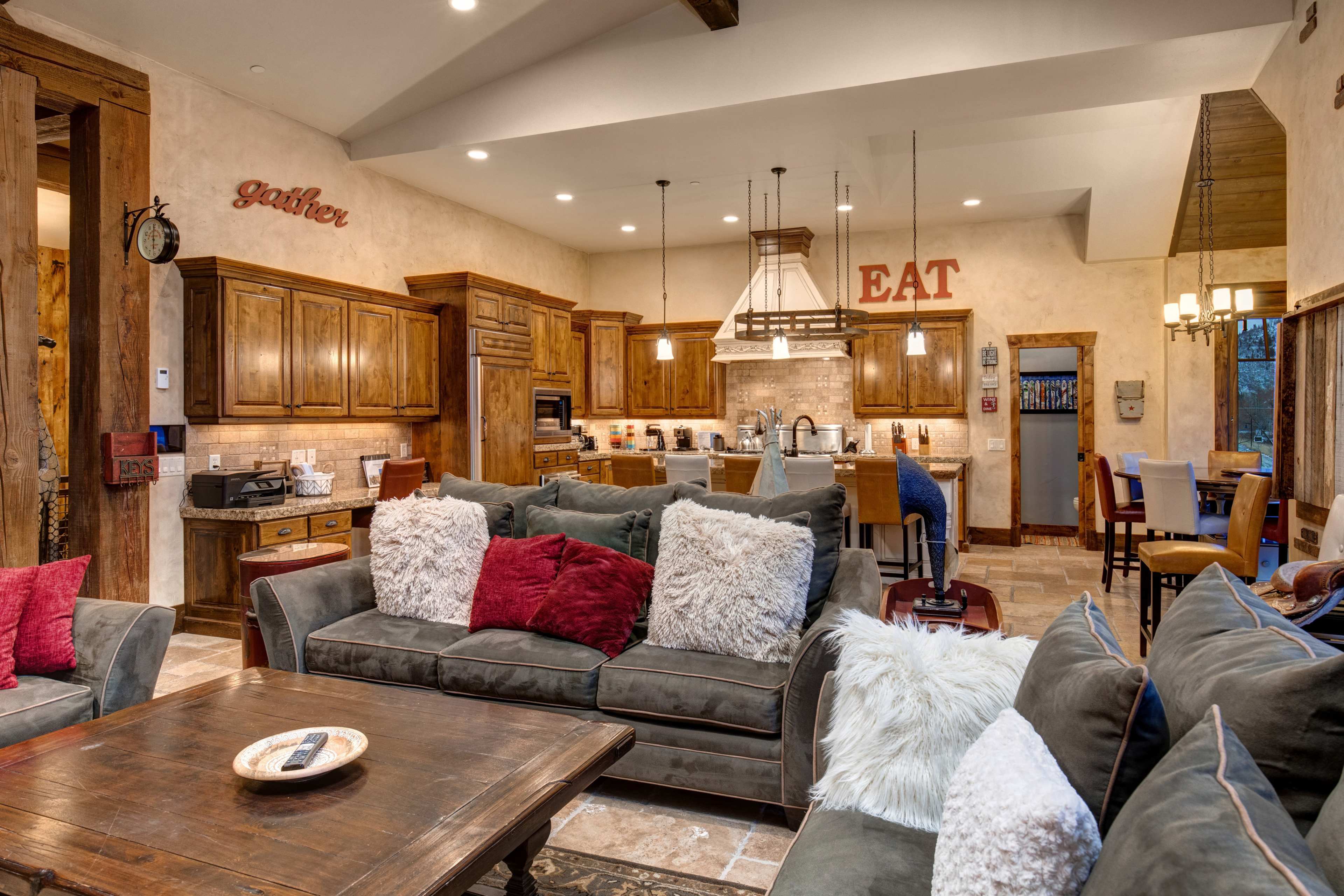 A well-furnished living space with a large seating area, a wooden dining table, and a spacious kitchen featuring wooden cabinets and modern appliances.