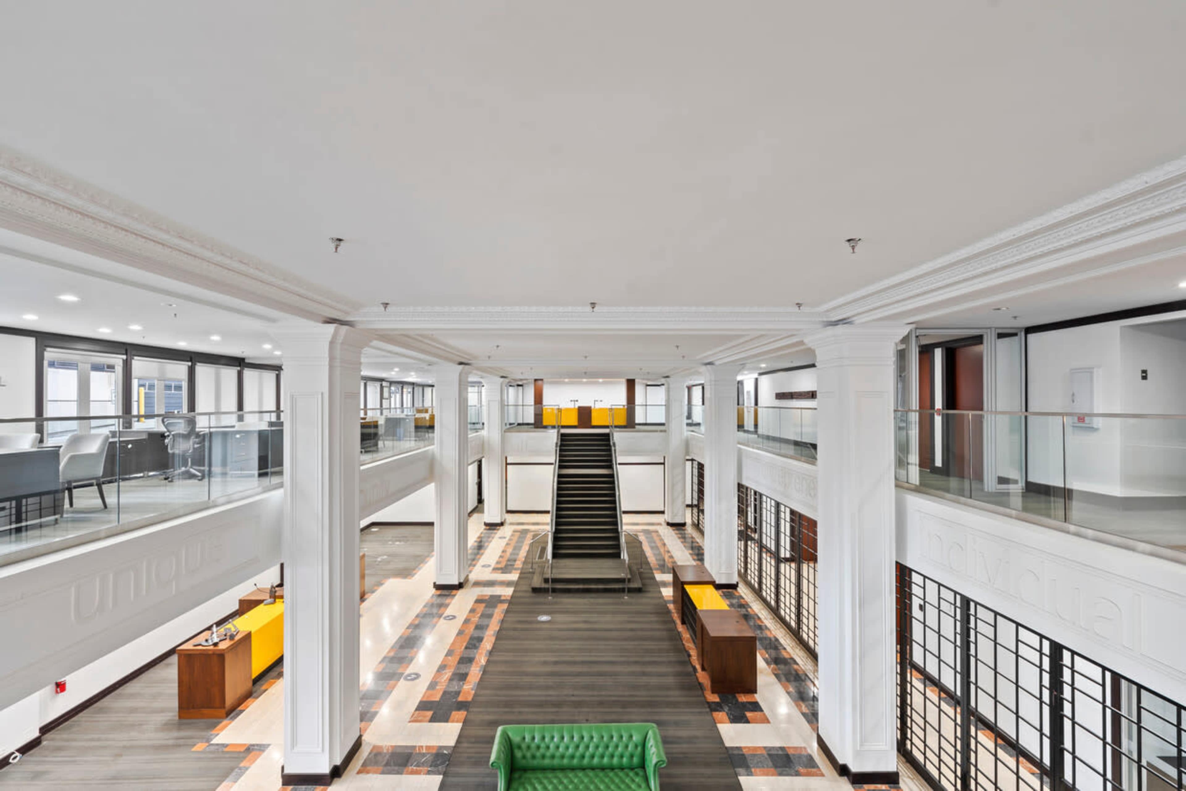 A modern interior space featuring a central staircase flanked by open areas and glass railings.