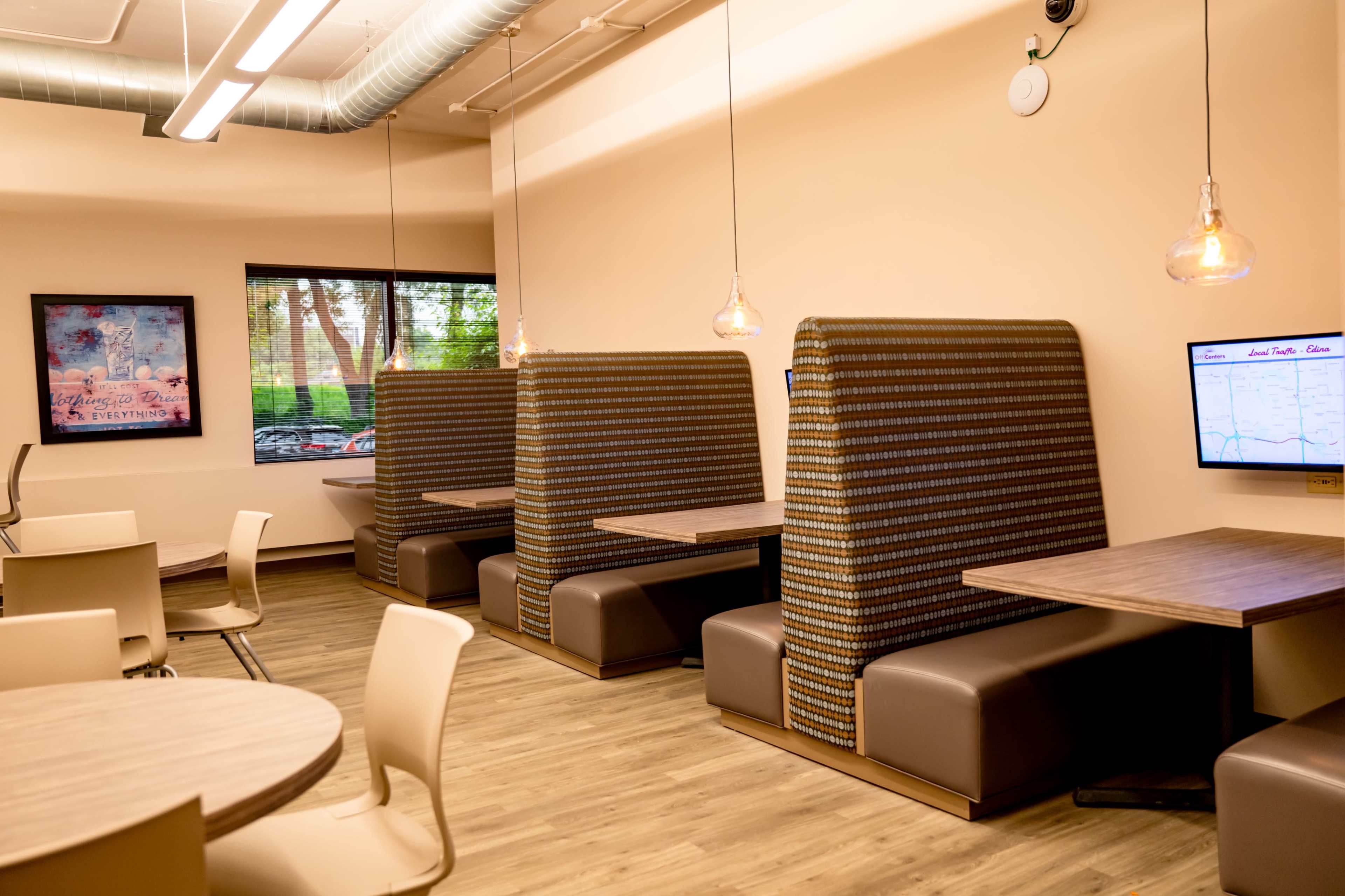 The image shows a modern cafe interior with booth seating, wooden tables, and pendant lighting.