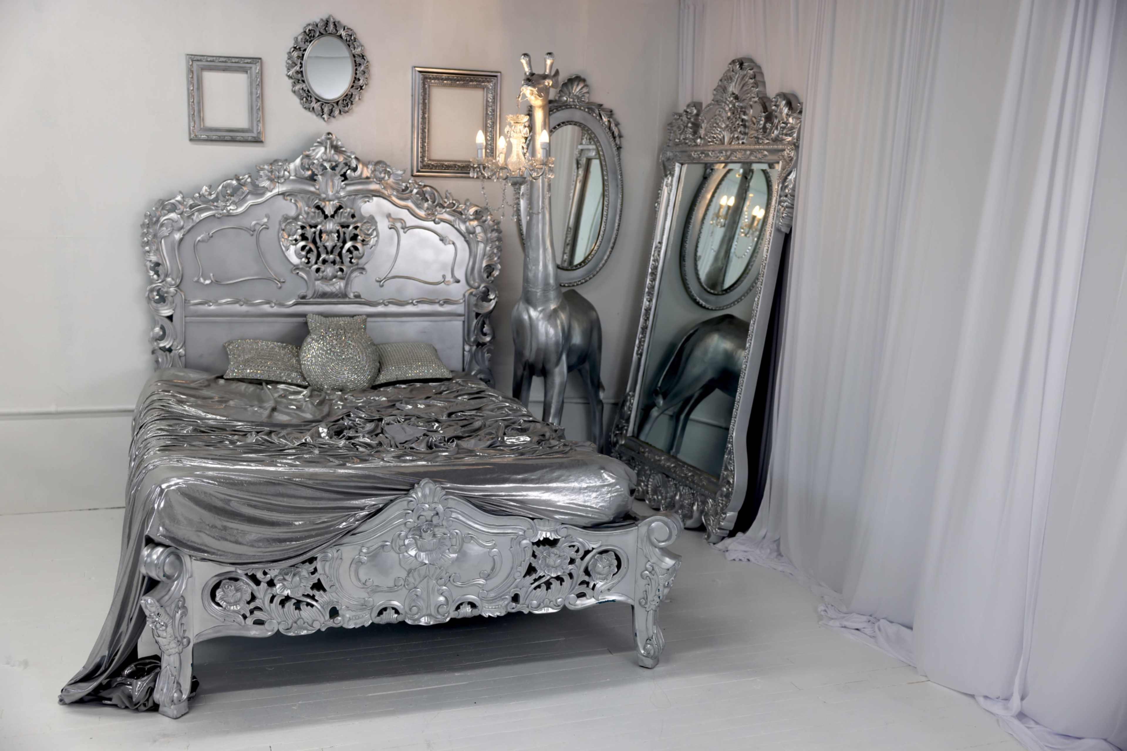 The image shows a silver-themed bedroom featuring an ornate bed, two large mirrors, and decorative wall accents.