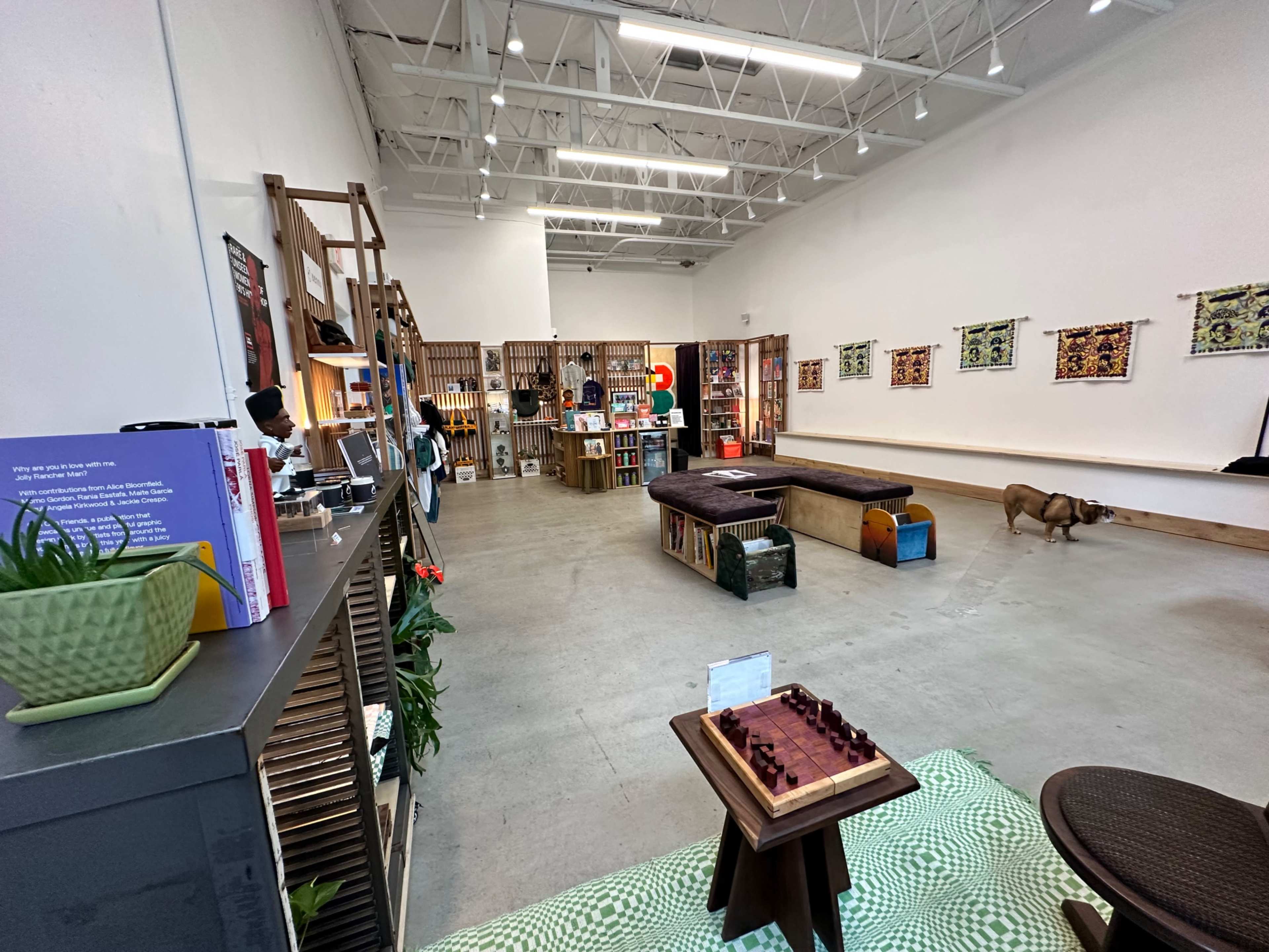 An interior of a retail space featuring a seating area, bookshelves, and various decorative items arranged throughout the room.