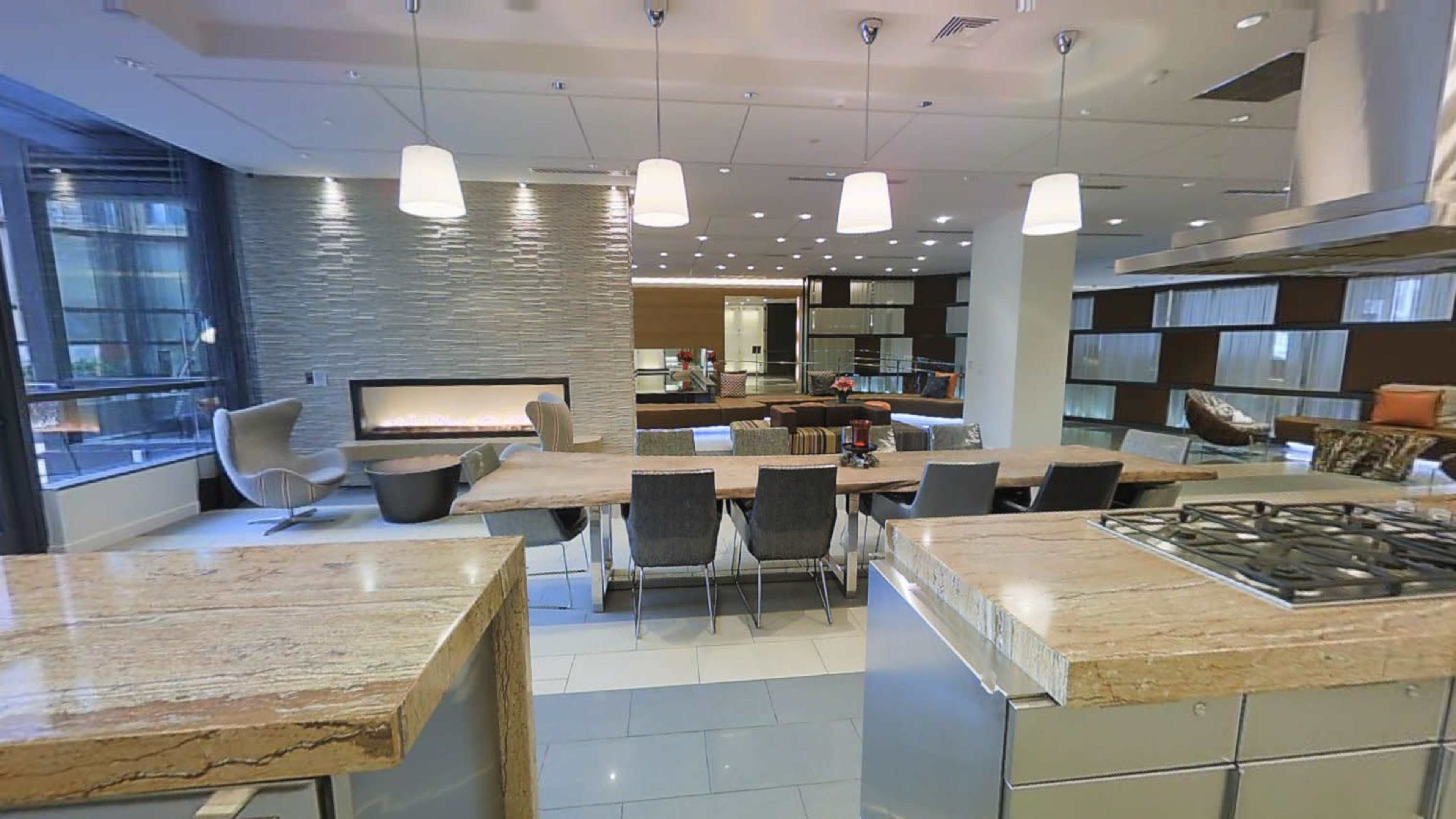 A modern kitchen and dining area with a long dining table, stone countertops, and a sleek fireplace.