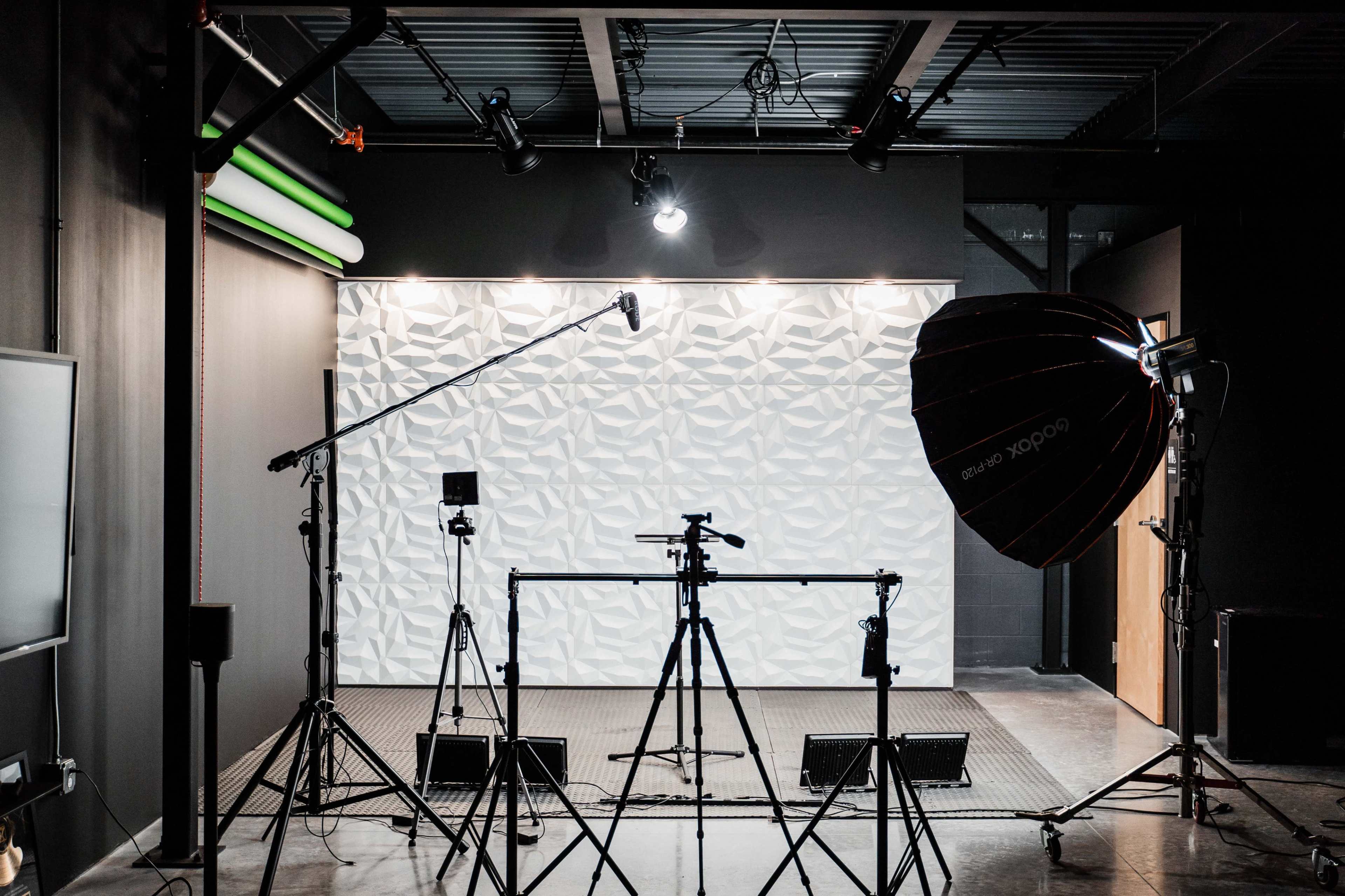 A photography studio is set up with tripods, lighting equipment, and a textured backdrop.