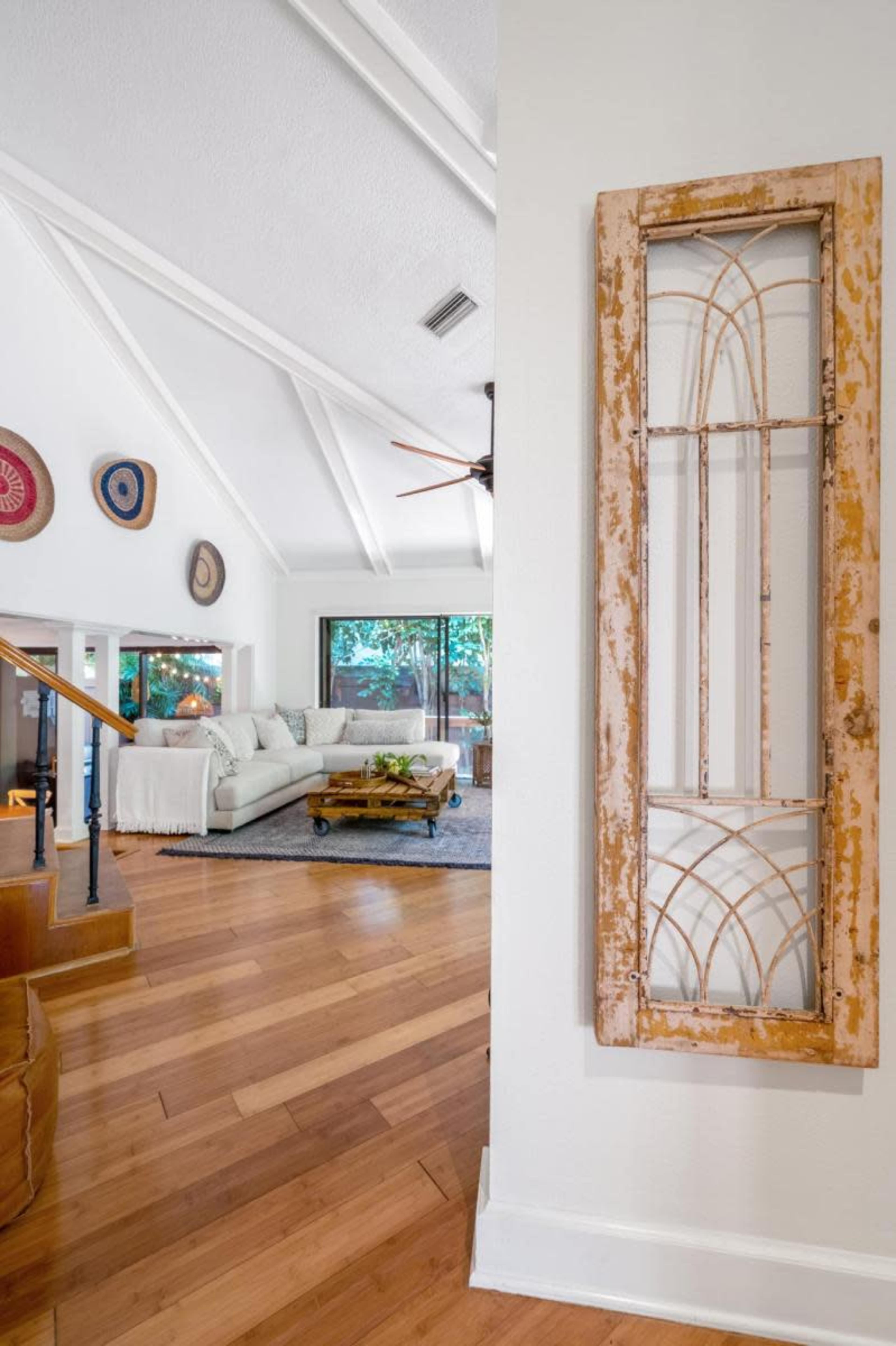 The image shows a living room with a sectional sofa and a wooden coffee table, framed by a decorative wall panel and visible through an archway.
