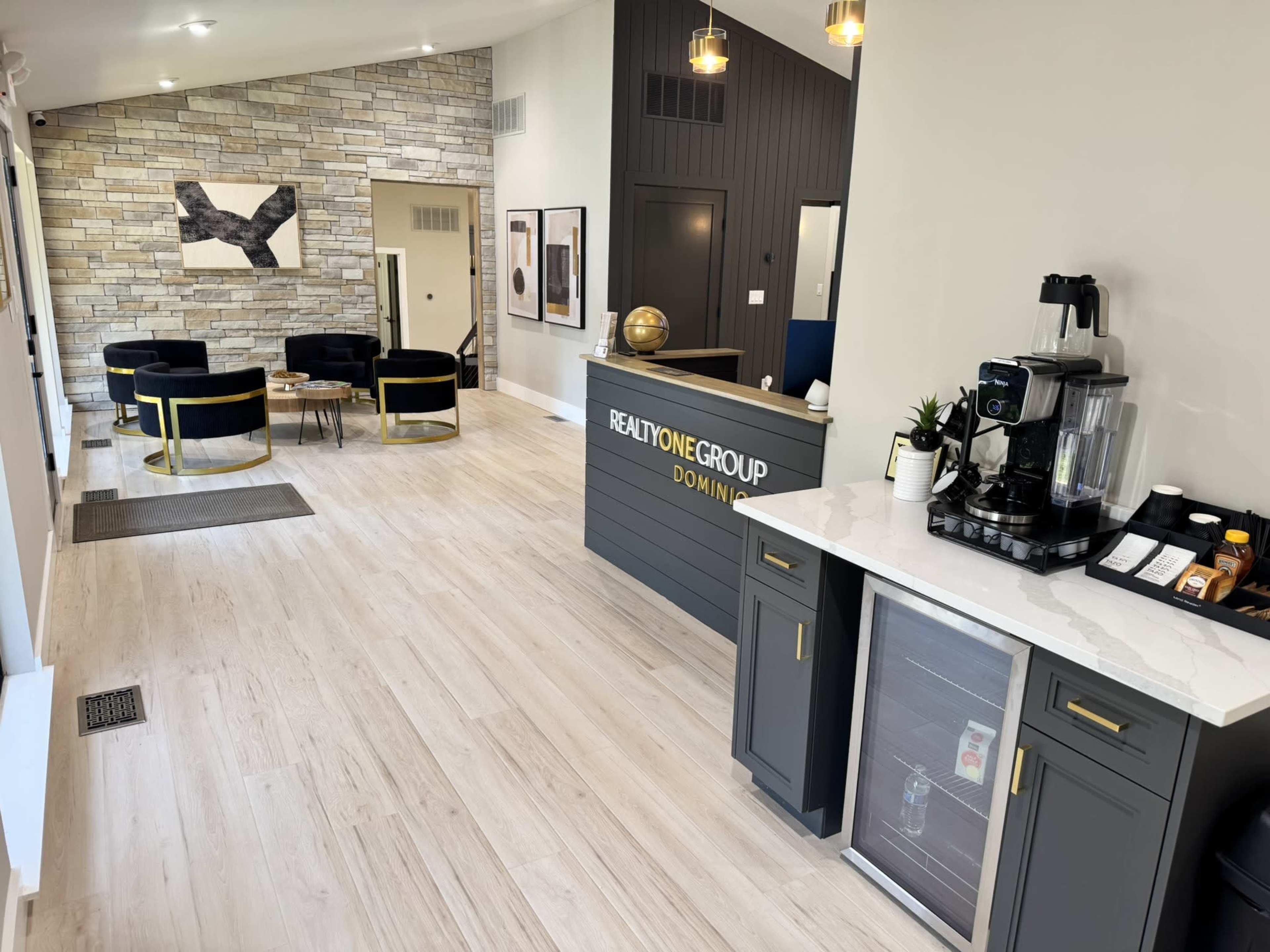 The image shows a modern office lobby with a reception desk, seating area, and decorative wall features.