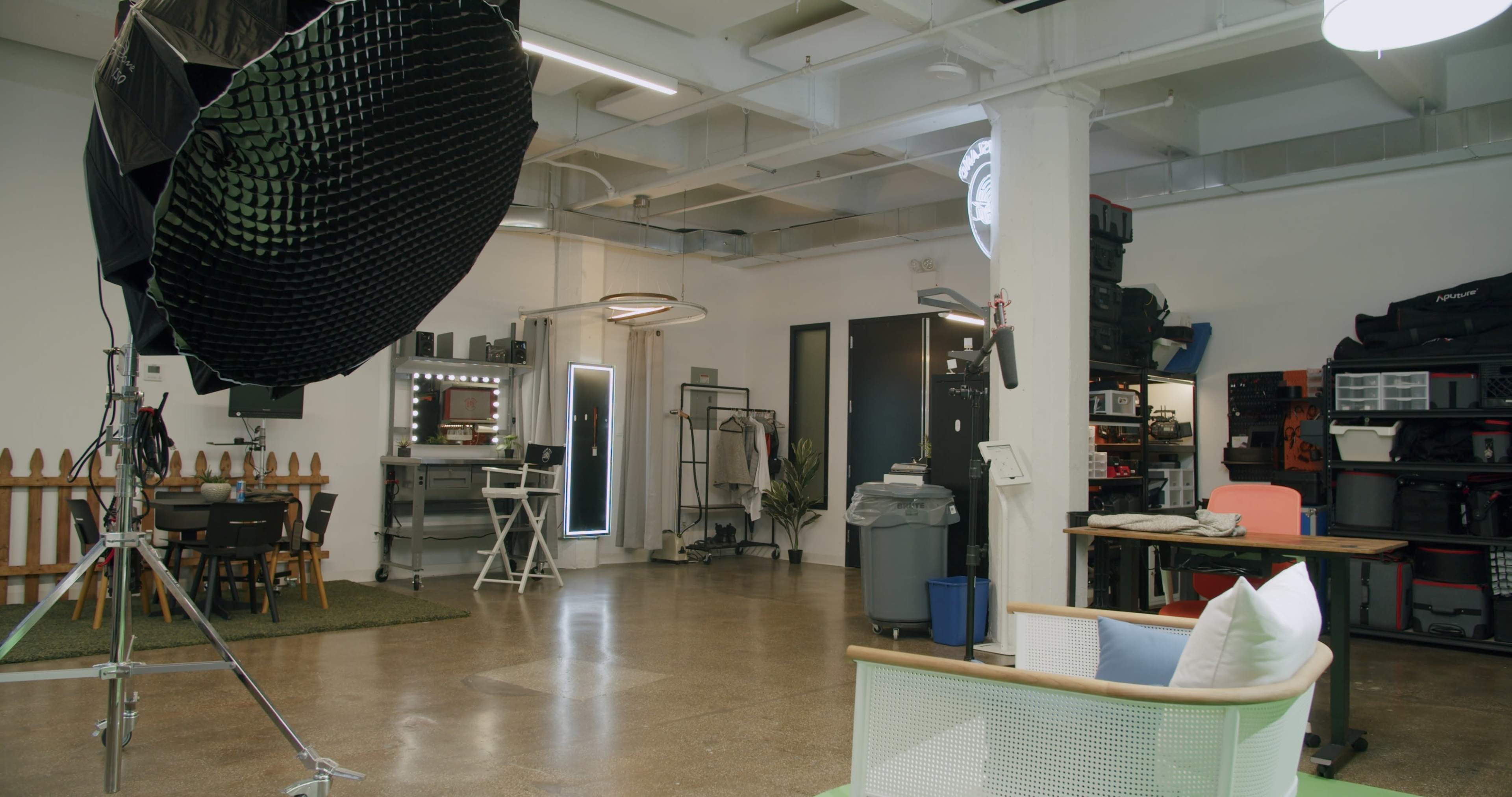 A modern studio space with photography equipment, casual seating, and storage areas.