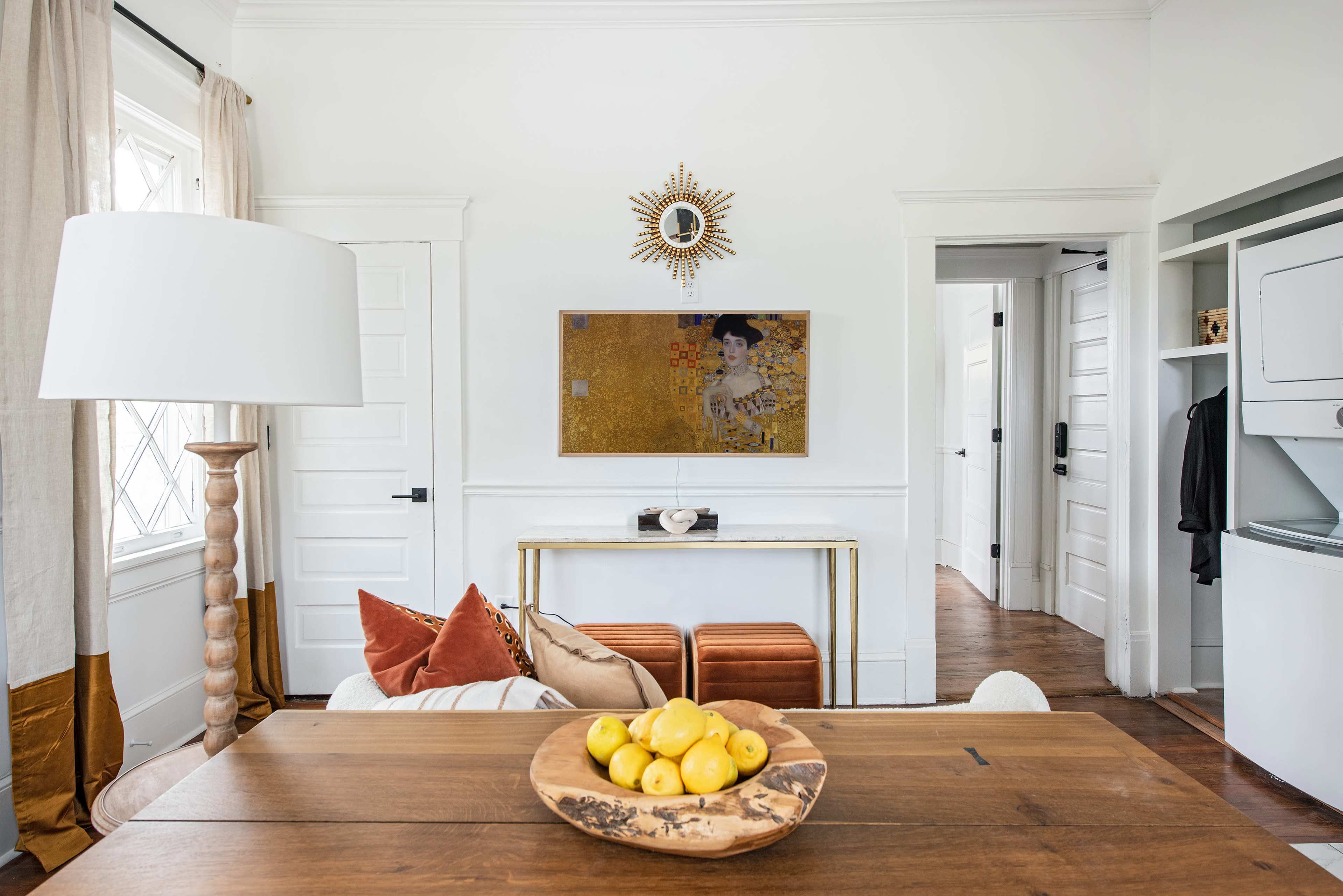The image shows a bright indoor room with a wooden dining table, a bowl of lemons, and a gold frame artwork on the wall.