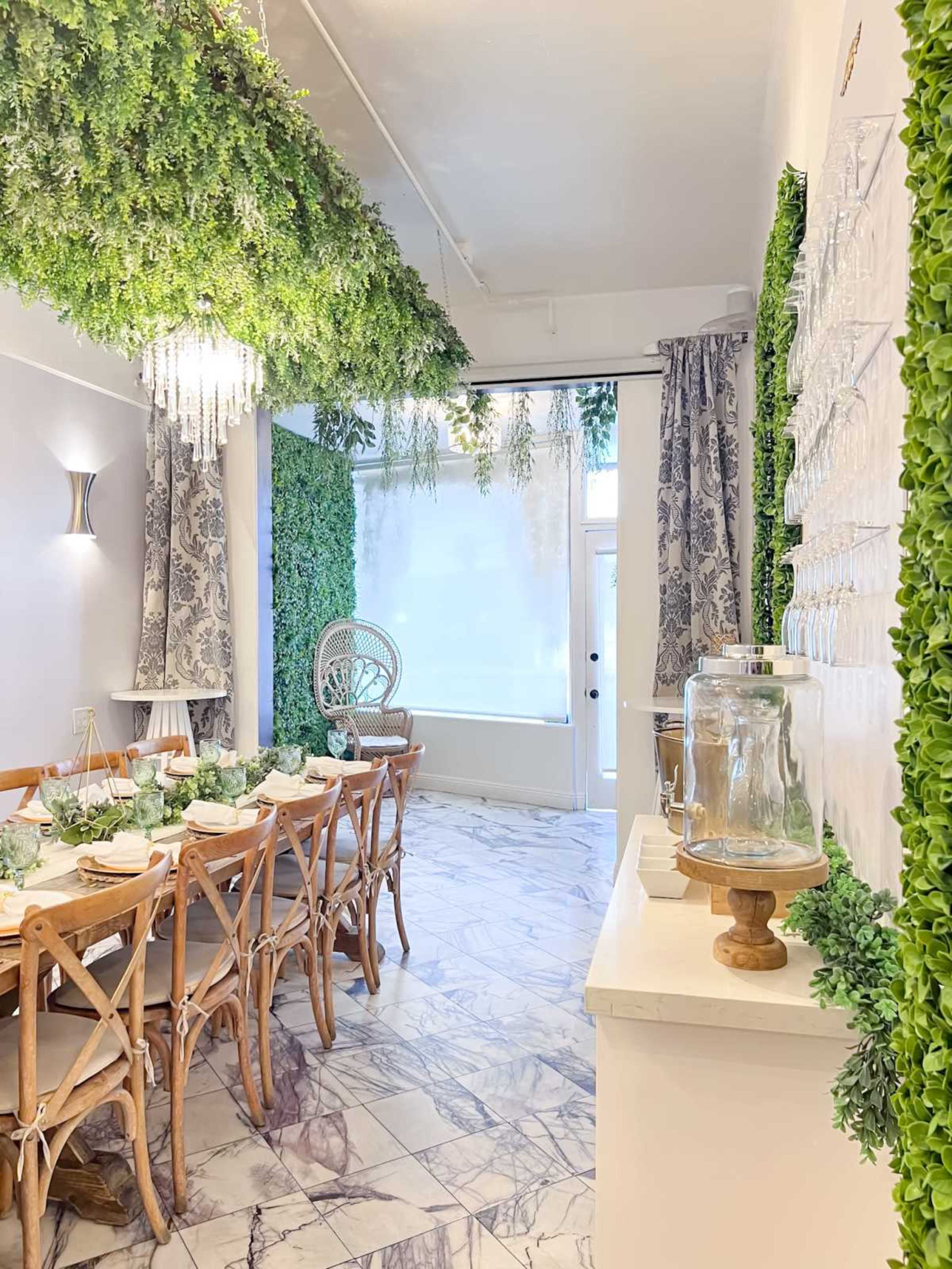 A beautifully arranged dining area features a long wooden table set for a meal, surrounded by greenery and elegant decor.