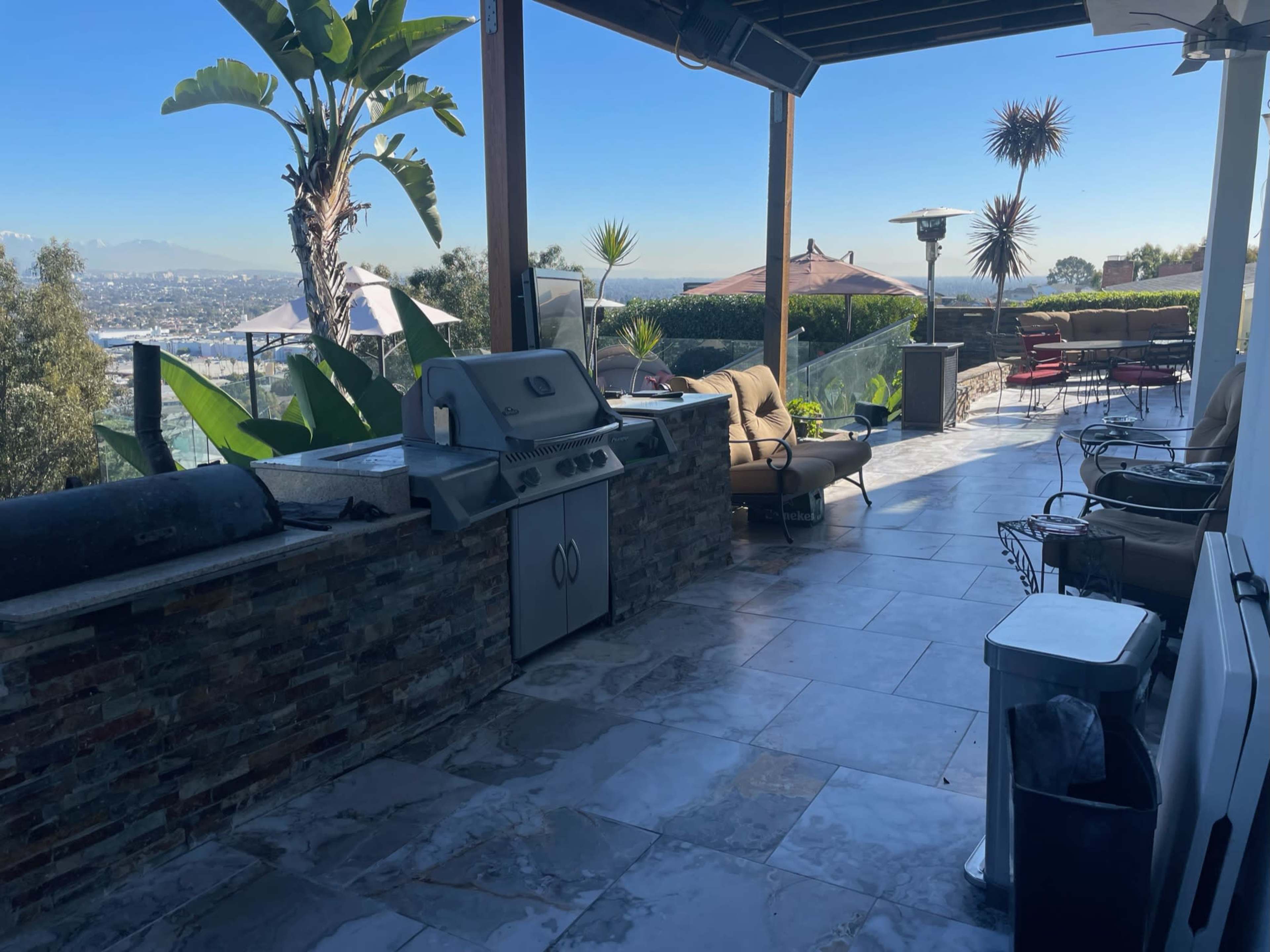 An outdoor patio with a stone grill, seating areas, and a view of the landscape beyond.