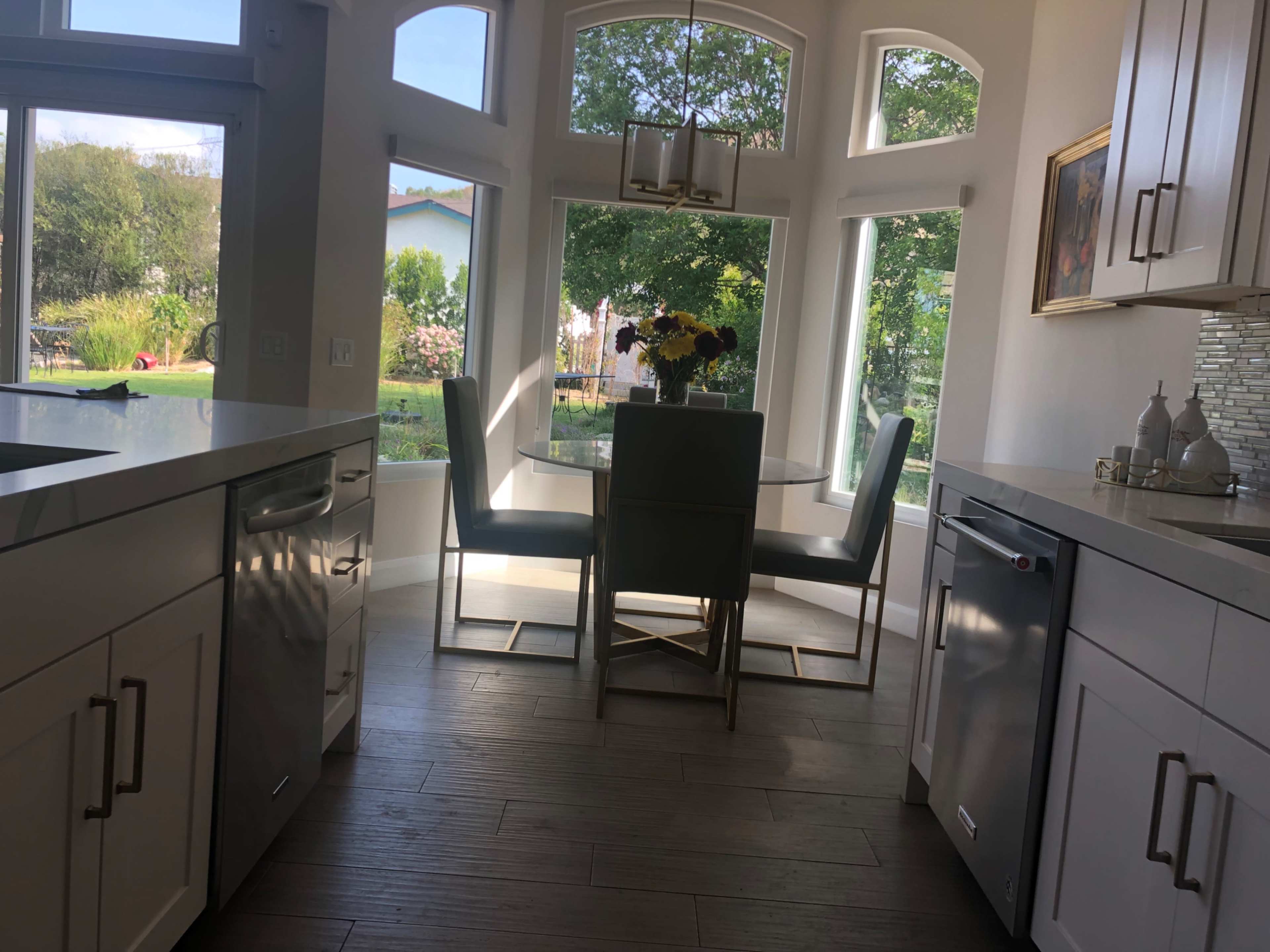 A modern kitchen with a dining table set near large windows that provide a view of the outdoors.