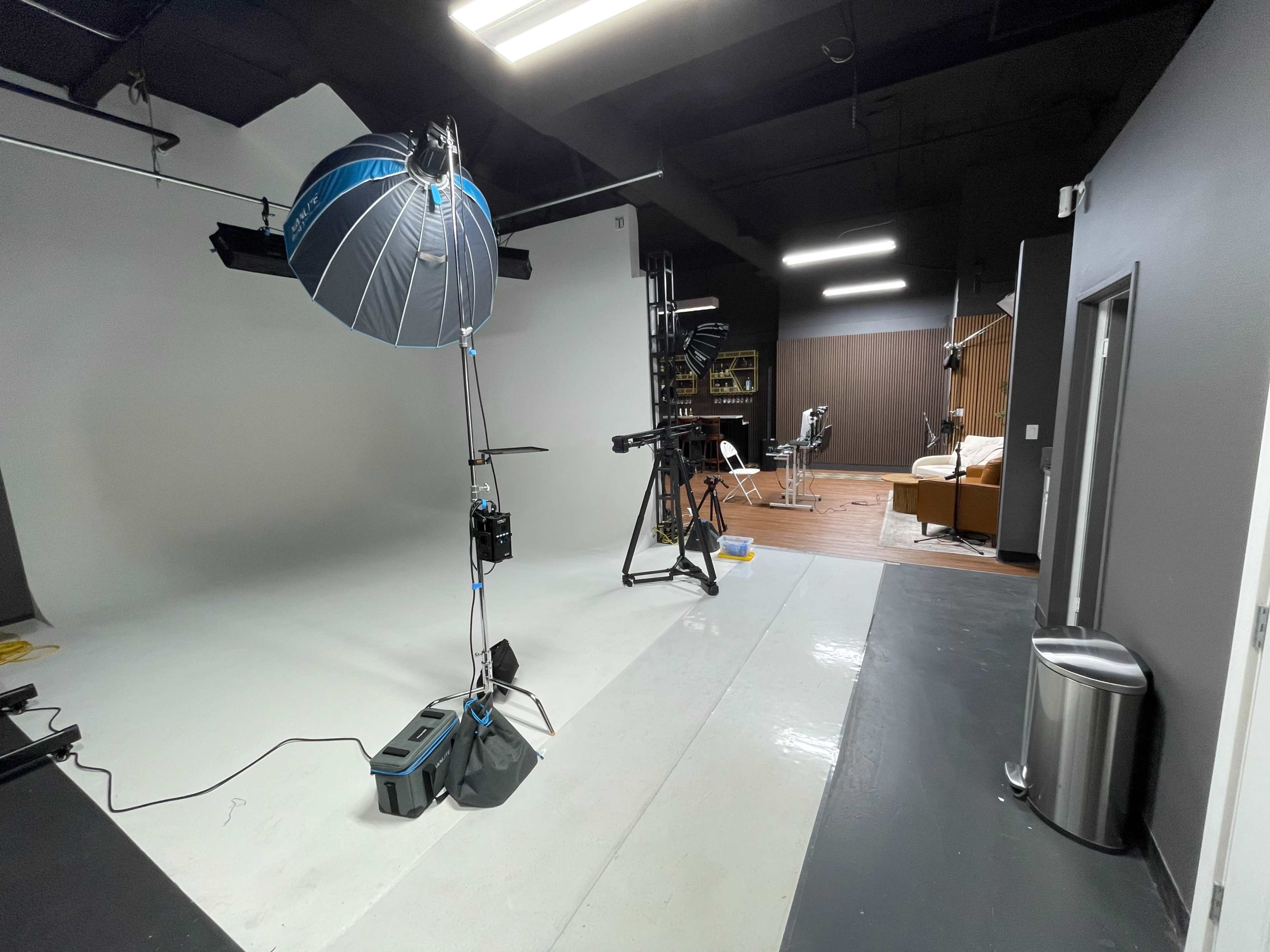 The image shows a photography studio equipped with a backdrop, lighting equipment, and various pieces of furniture and gear arranged for a shoot.