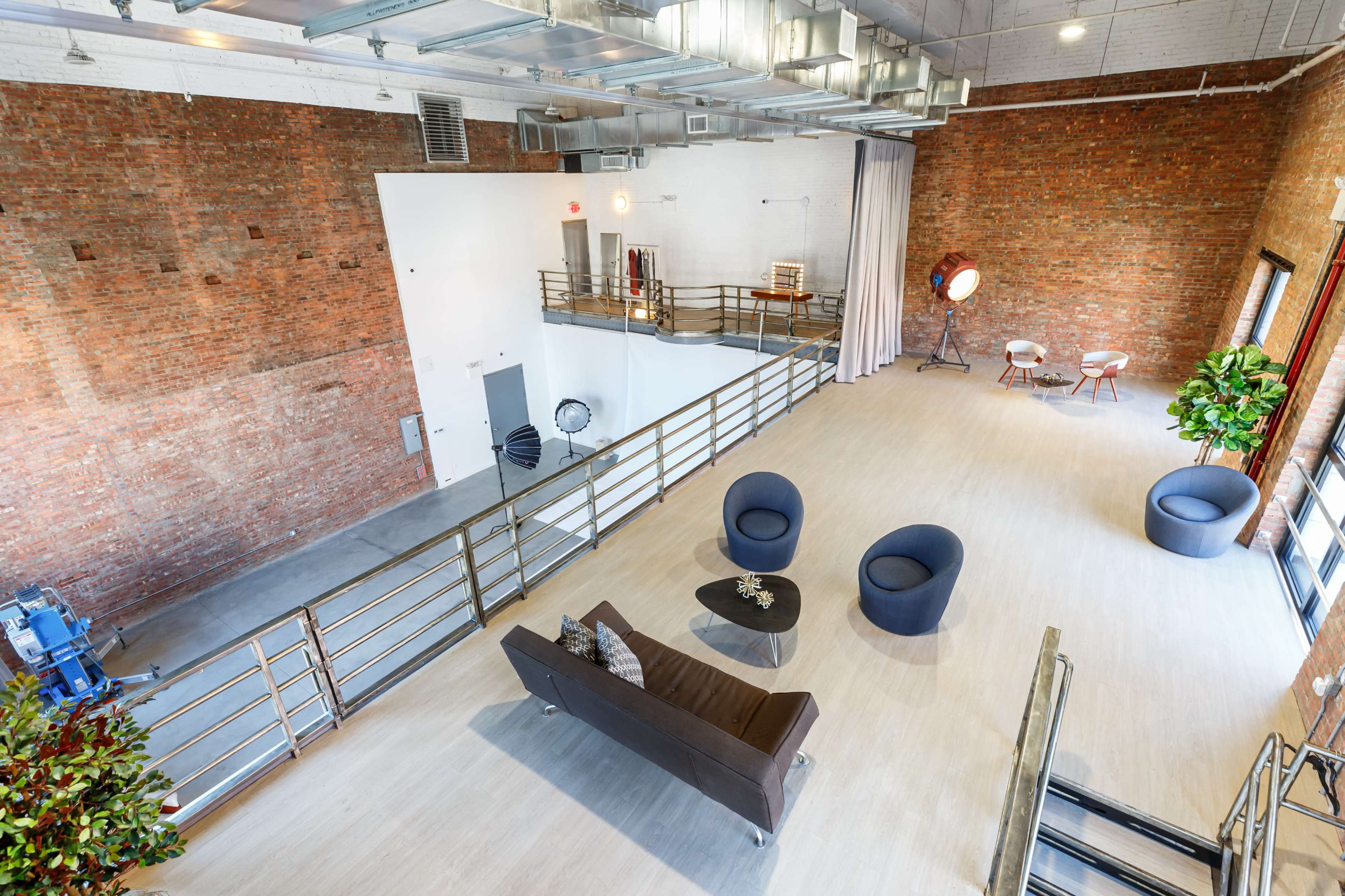 A spacious loft with exposed brick walls, a modern seating area, and large windows allowing natural light.