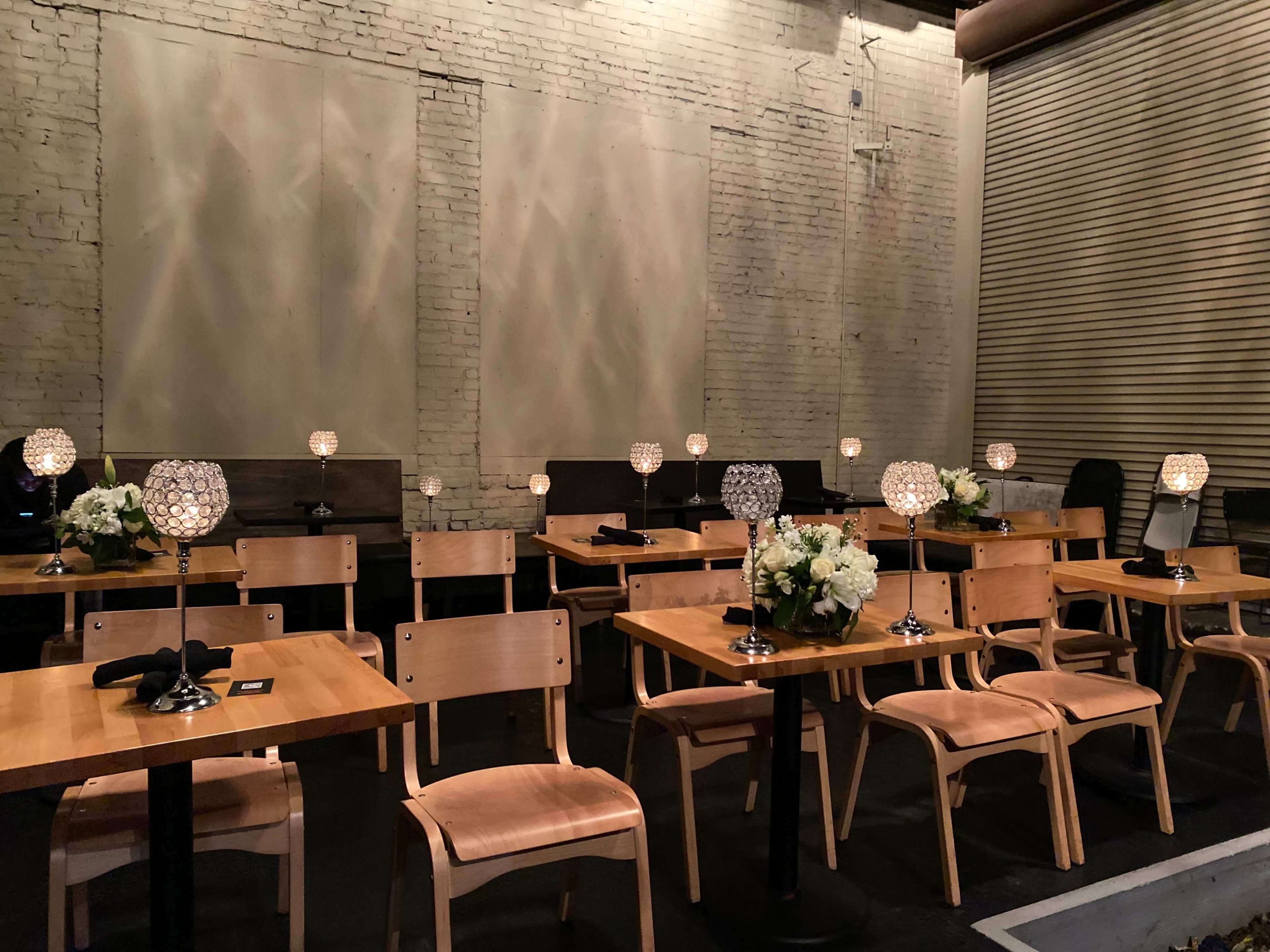 A dining area features rows of wooden tables and chairs, each adorned with a decorative lamp and a floral centerpiece.