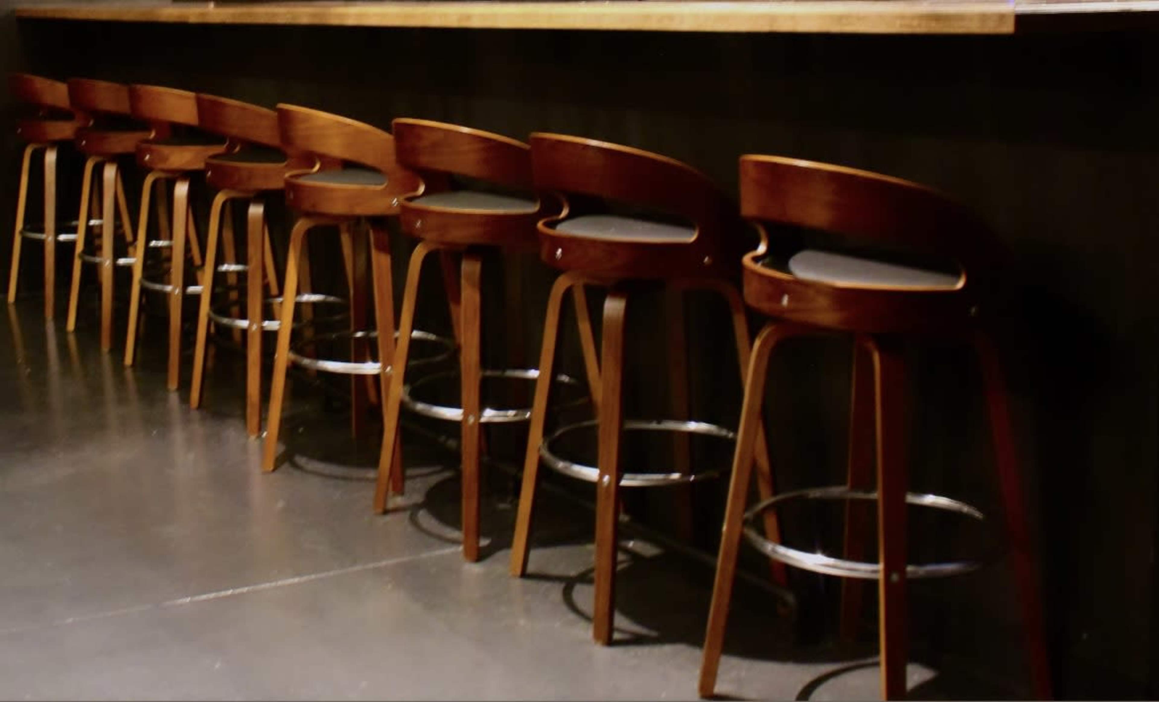 A row of wooden bar stools lined up along a countertop.