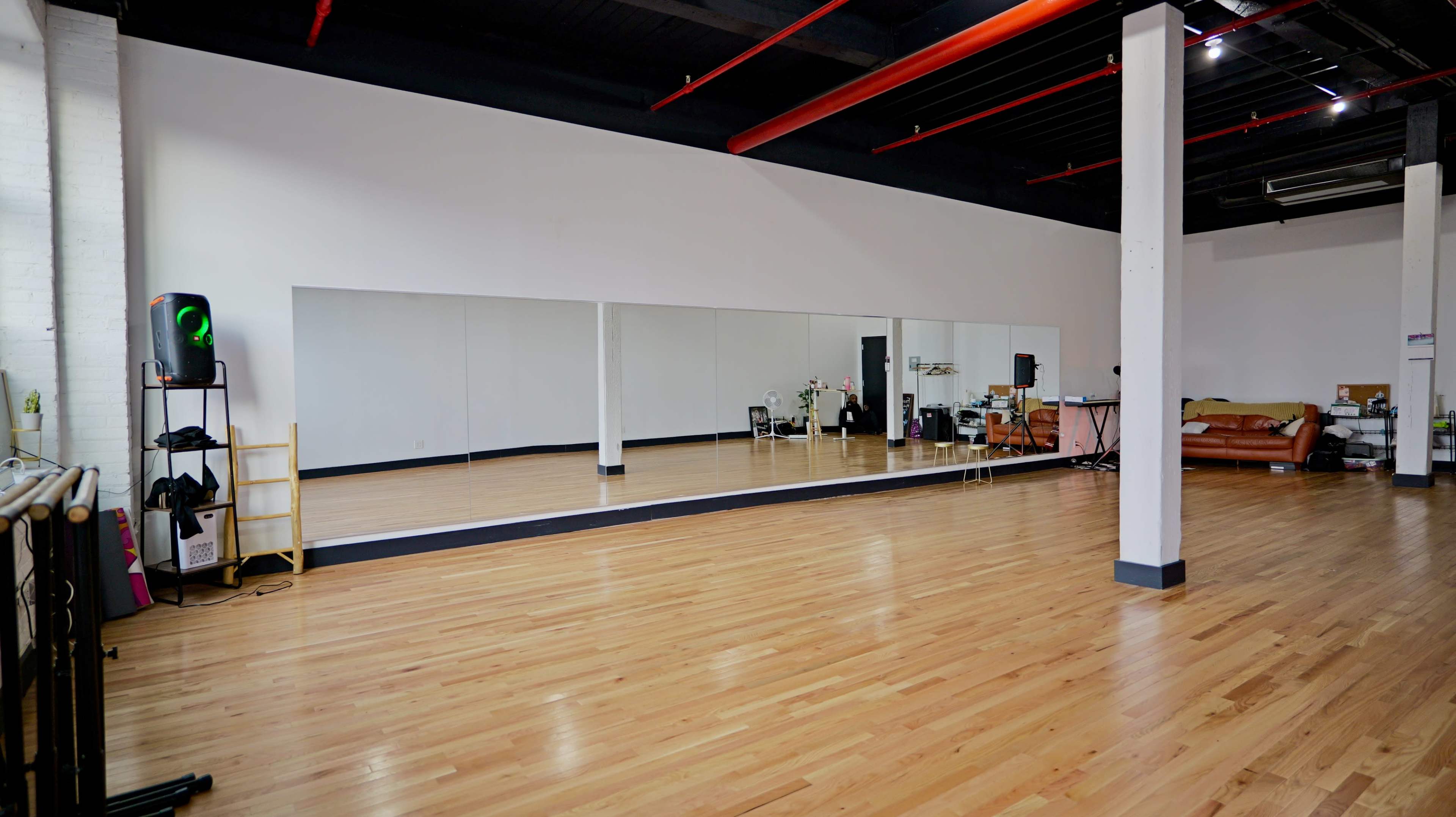 The image shows a spacious dance studio with large mirrors on one wall and polished wooden floors.