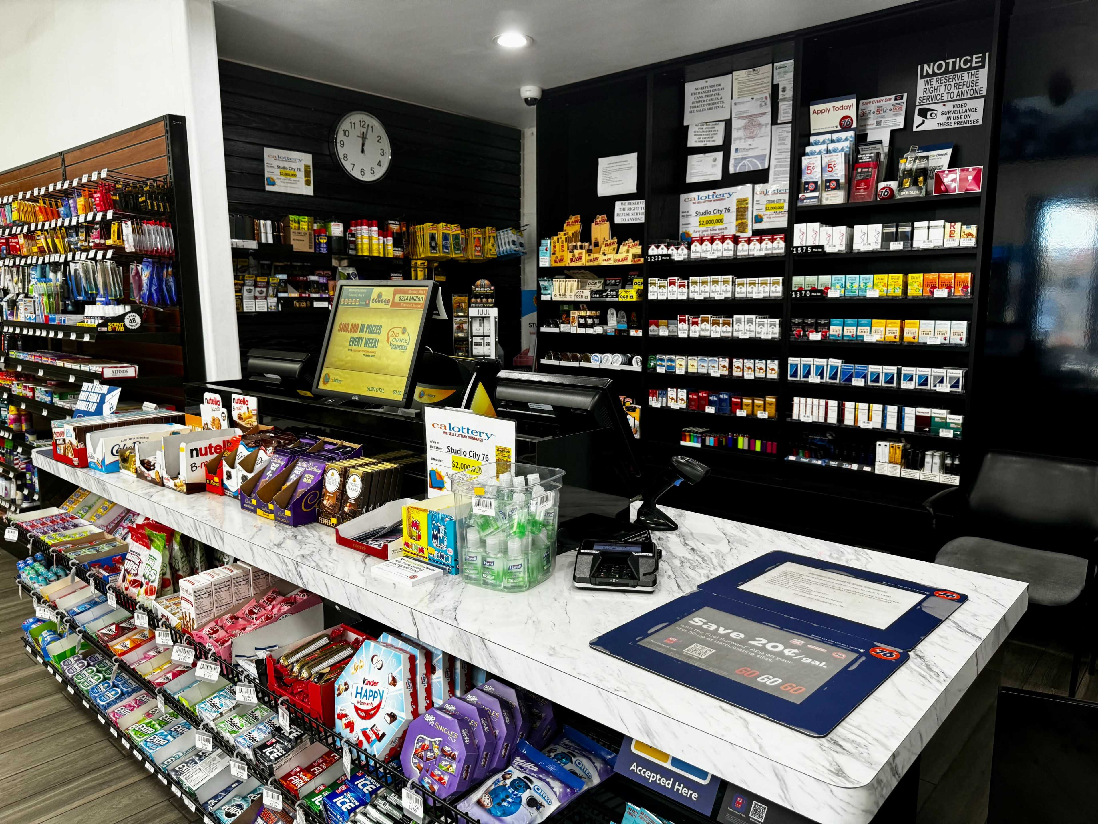 A pharmacy counter displays a variety of products, including health items, snacks, and beverages, organized neatly on shelves in the background.