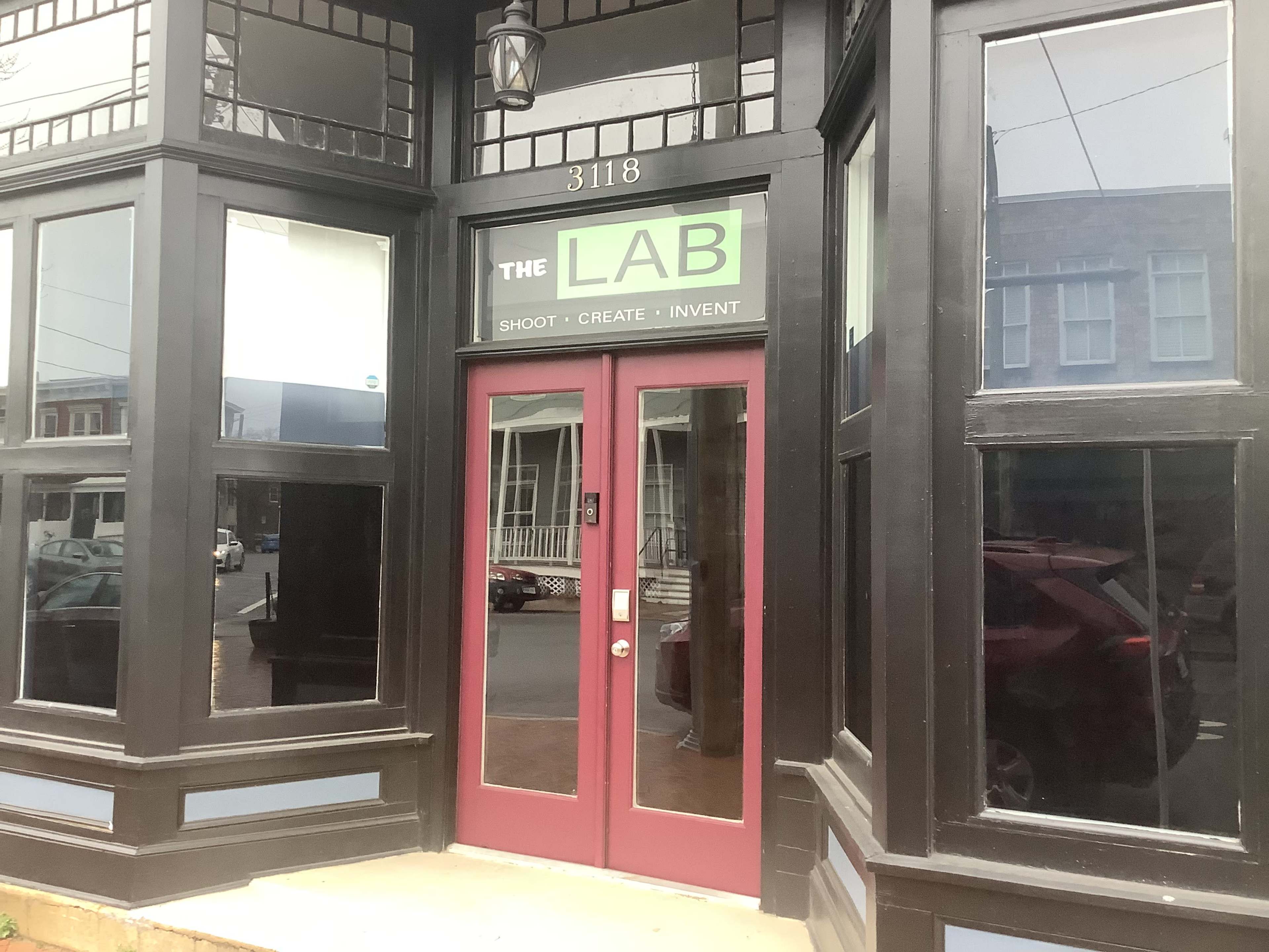 The entrance to a business named "The LAB," featuring a maroon door and large windows.