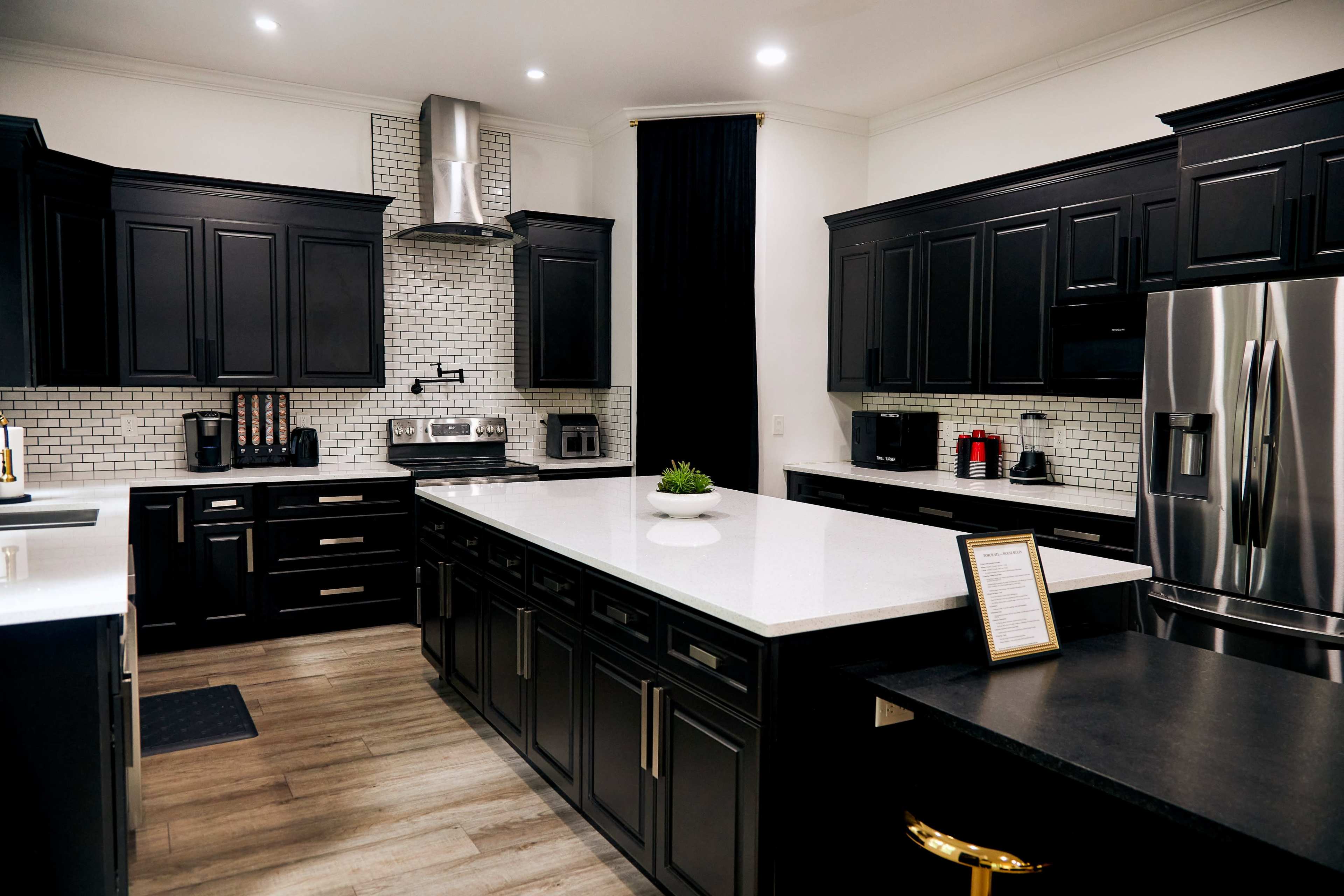 The kitchen features dark cabinetry, a central island with a white countertop, and stainless steel appliances.