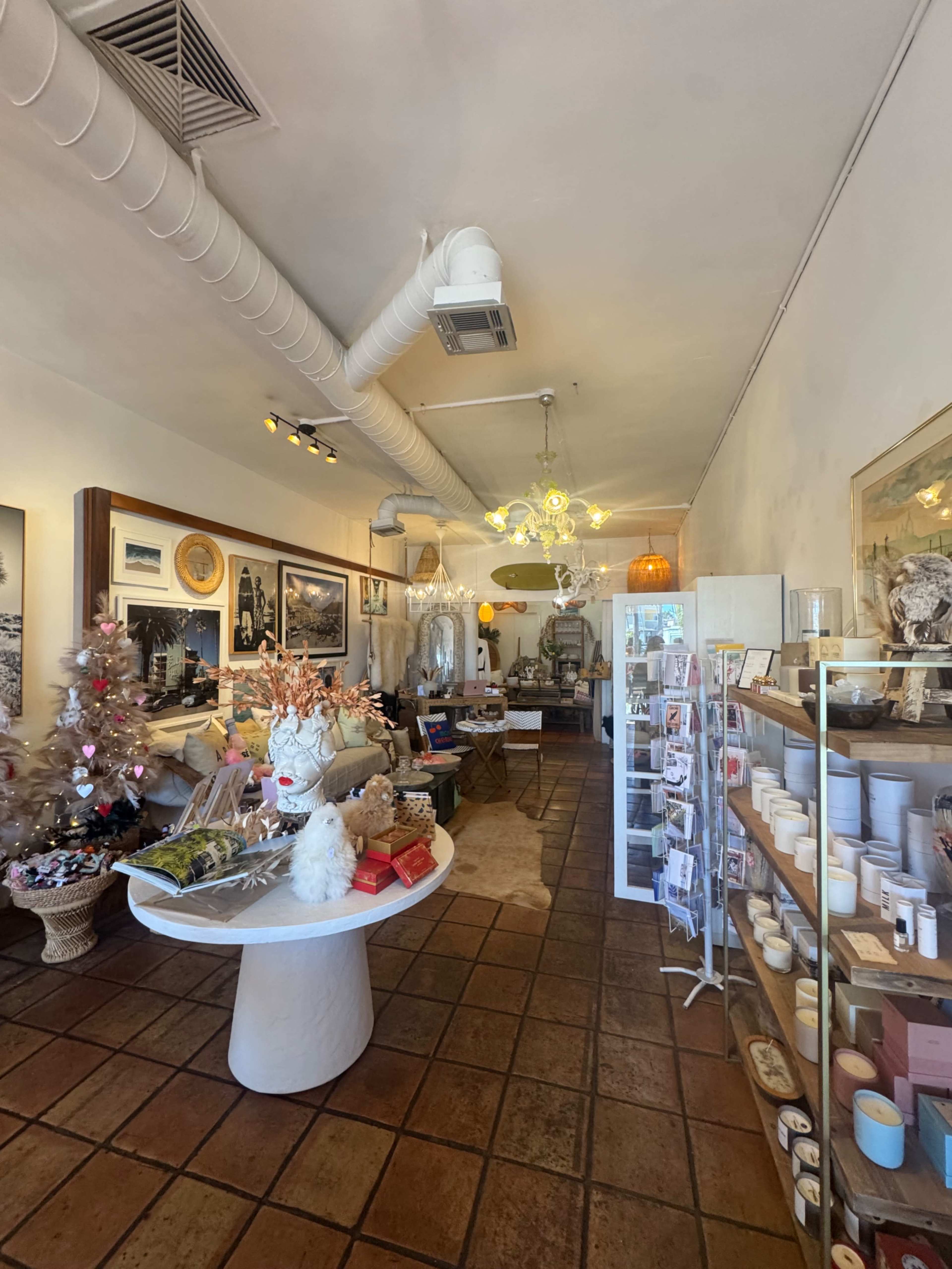 The interior of a retail store features decorative items, a table with gifts, and a display shelving unit filled with various products.
