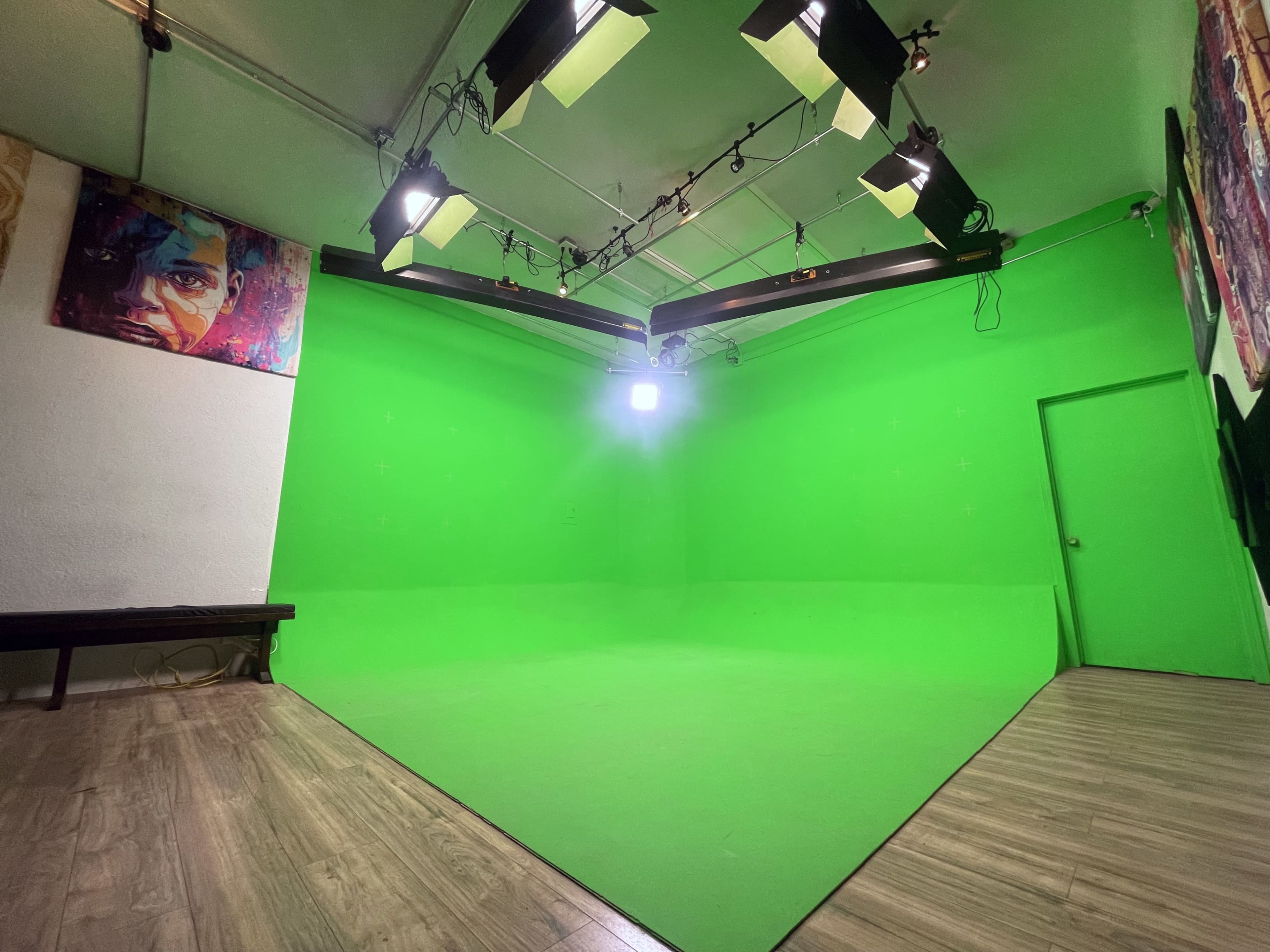 A green screen studio with overhead lights and a door on the right side.
