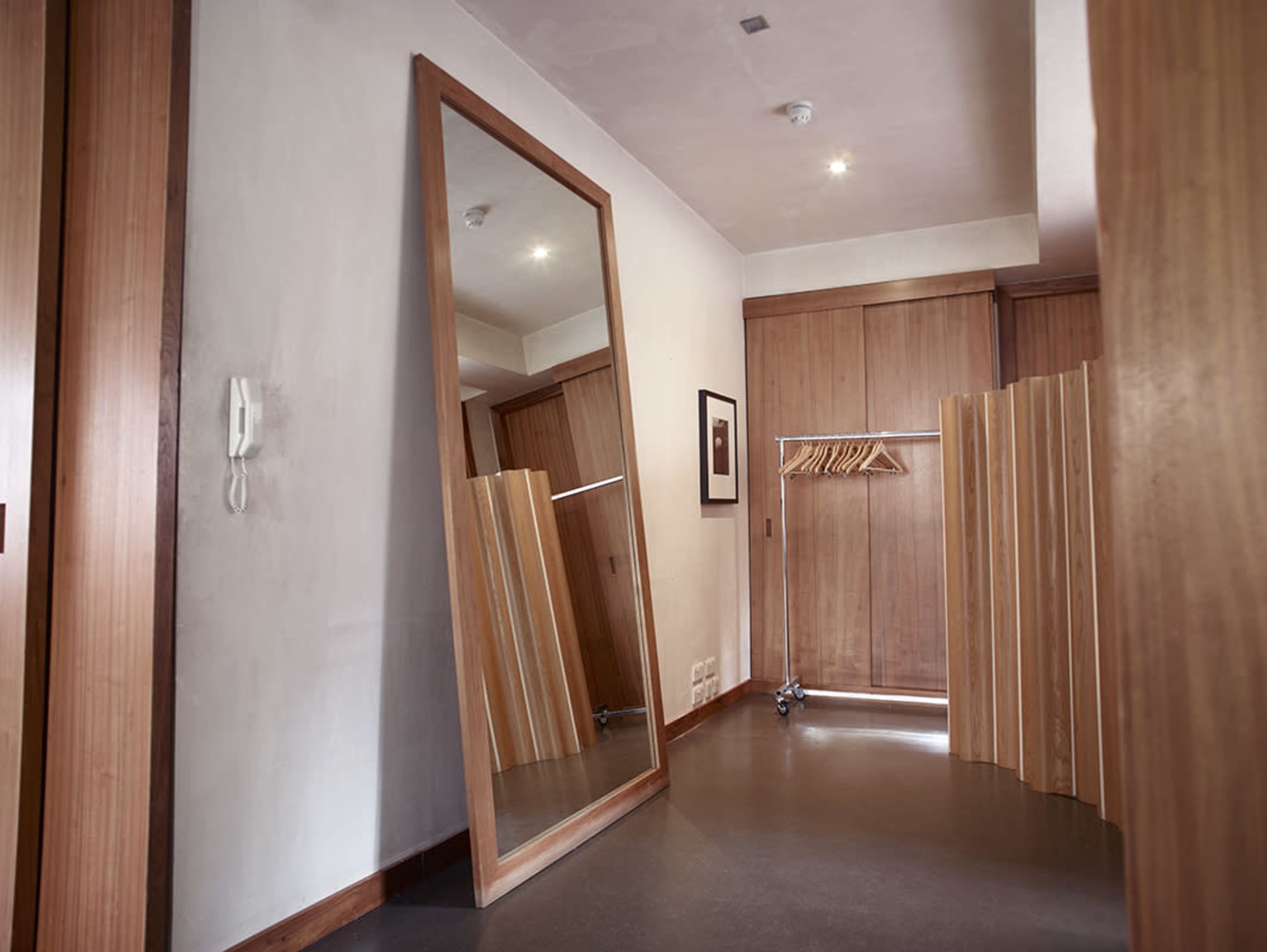 The image shows a spacious dressing area featuring a large mirror, wooden sliding doors, and a folding screen with hangers.
