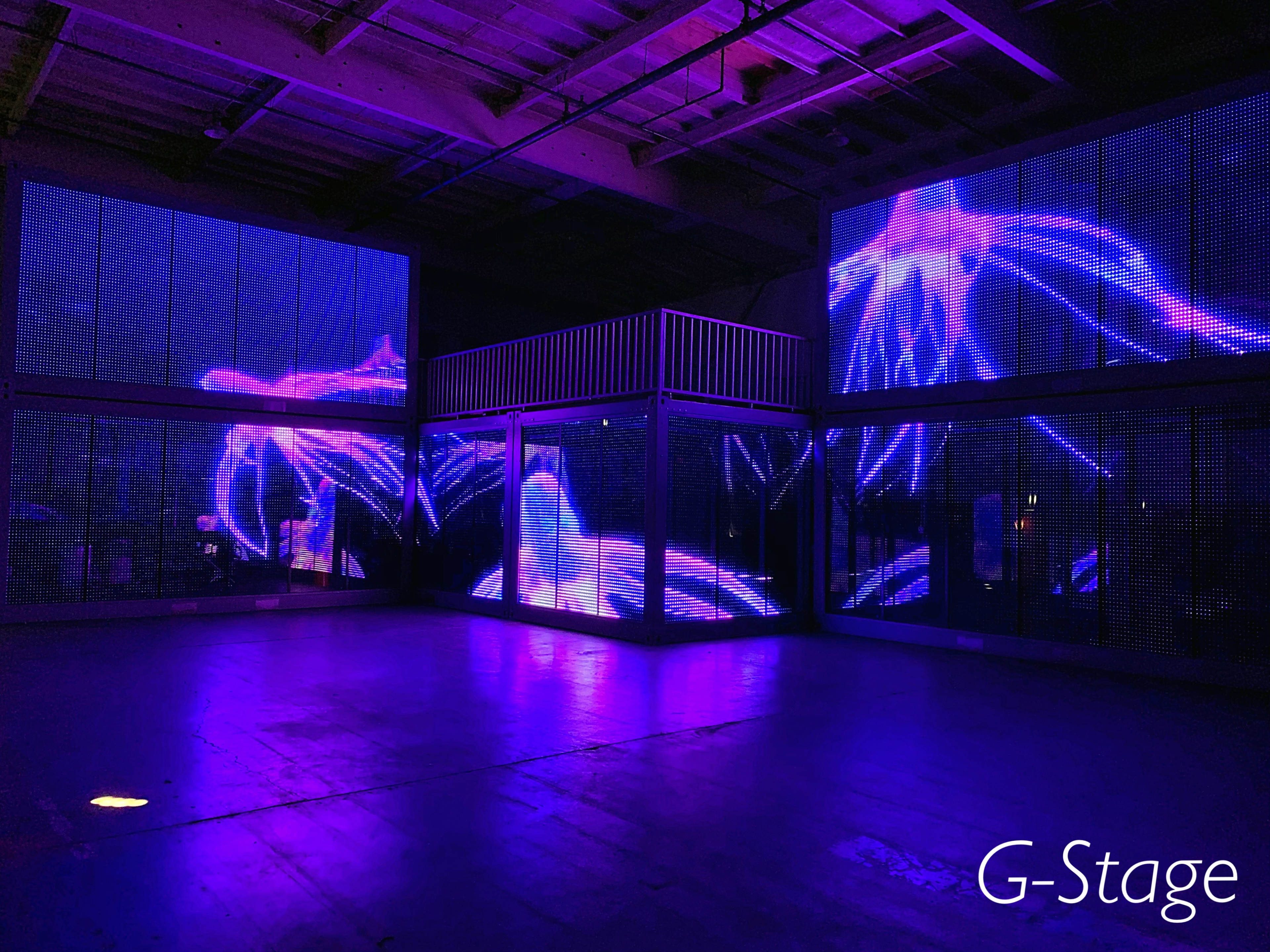 An industrial space with large screens displaying vibrant, abstract purple visuals.