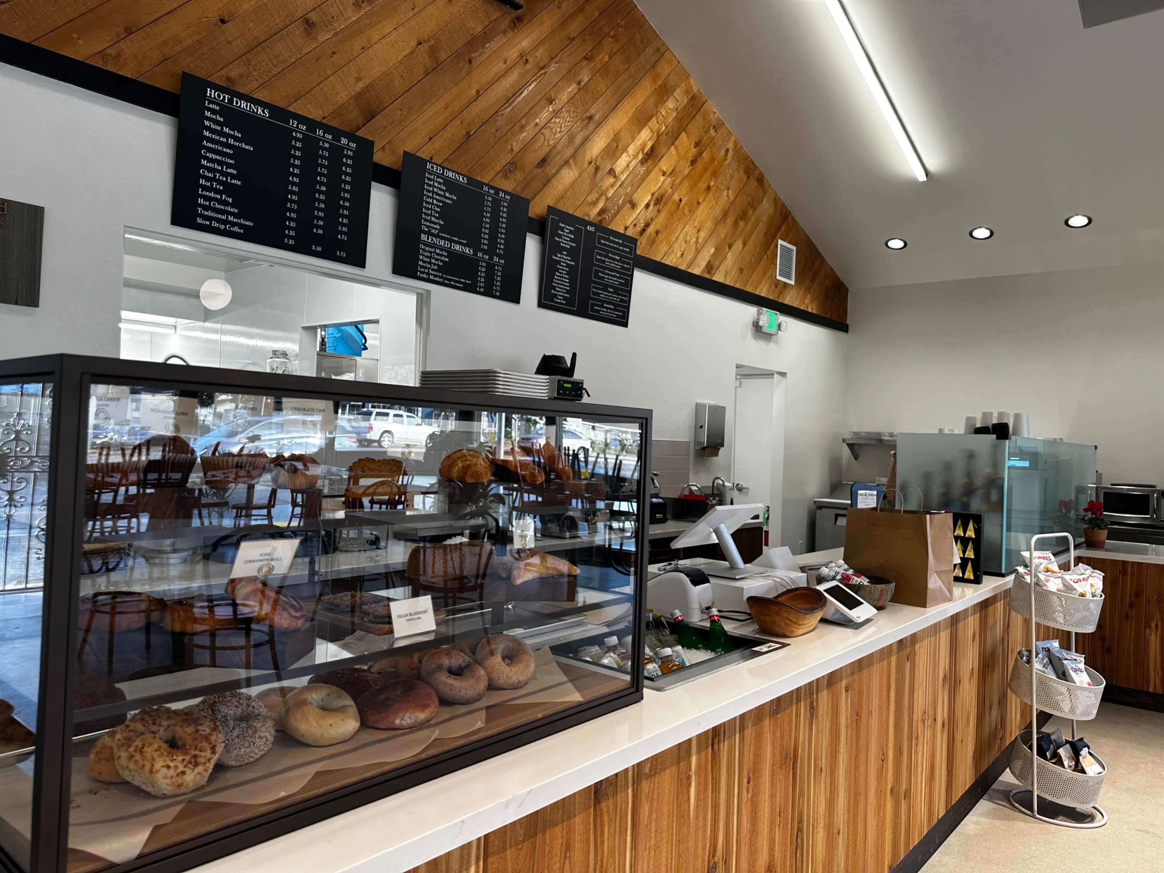 A bakery interior with a display case of baked goods and a menu board hanging above the counter.